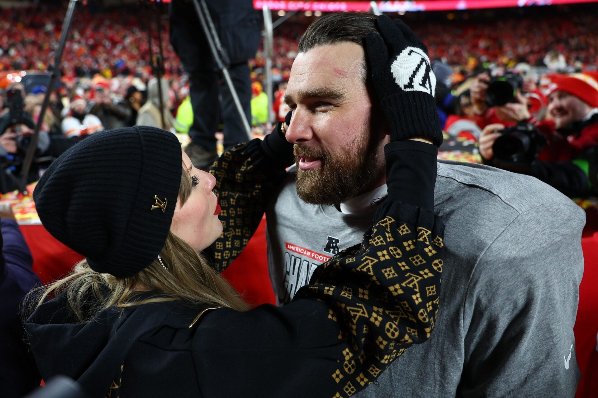 Recording artist Taylor Swift  and Kansas City Chiefs tight end Travis Kelce (87) react after the AFC Championship game against the Buffalo Bills at GEHA Field at Arrowhead Stadium.