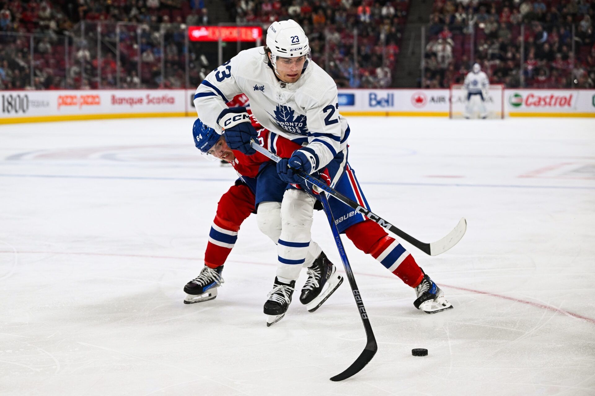 Toronto Maple Leafs left wing Matthew Knies (23) plays the puck against Montreal Canadiens defenseman David Reinbacher (64) during the third period at Bell Centre.