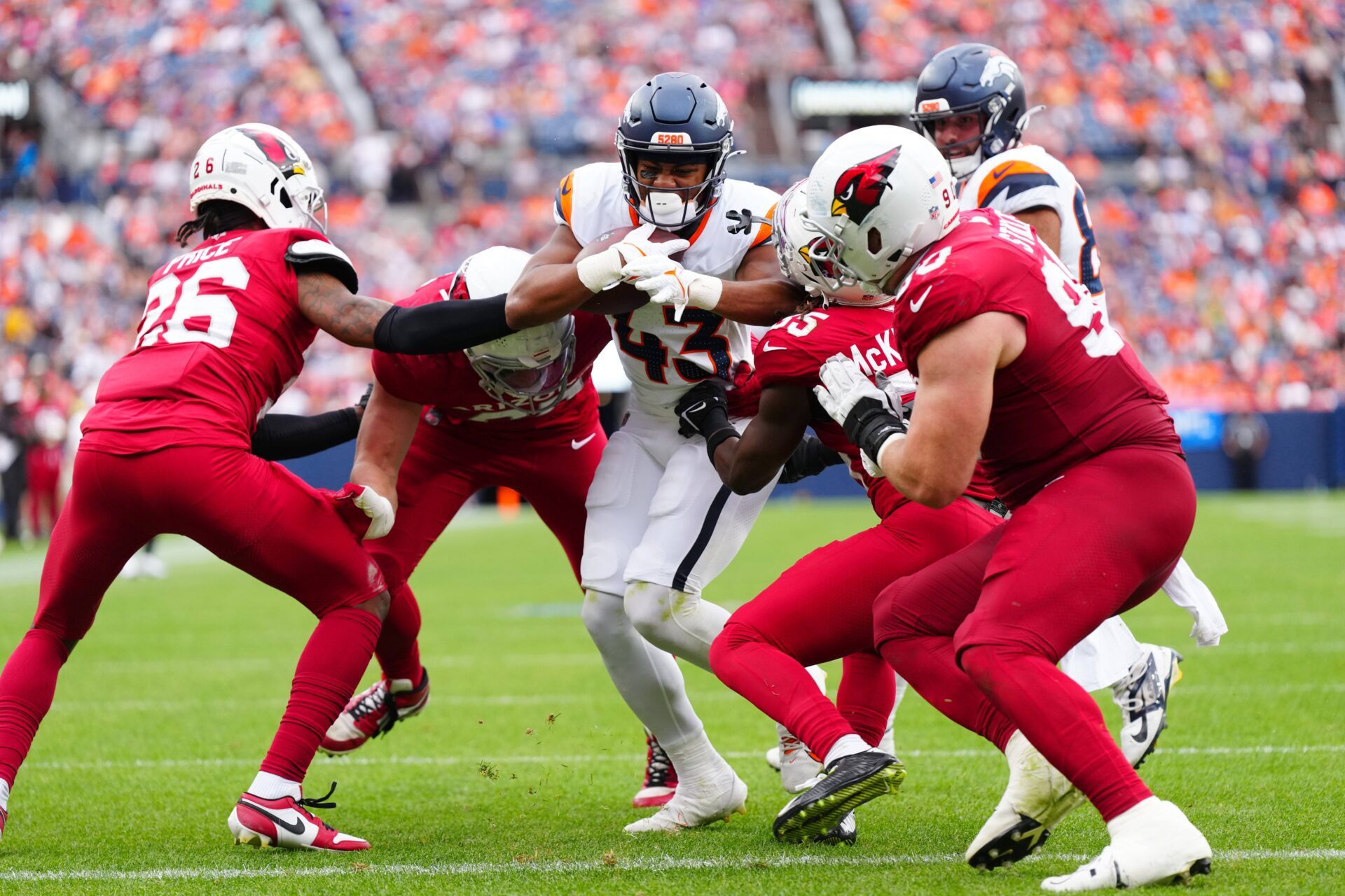 Denver Broncos running back Blake Watson (43) rushes against Arizona Cardinals cornerback Bobby Price (26) and defensive tackle Dante Stills (55) in the second half at Empower Field at Mile High.