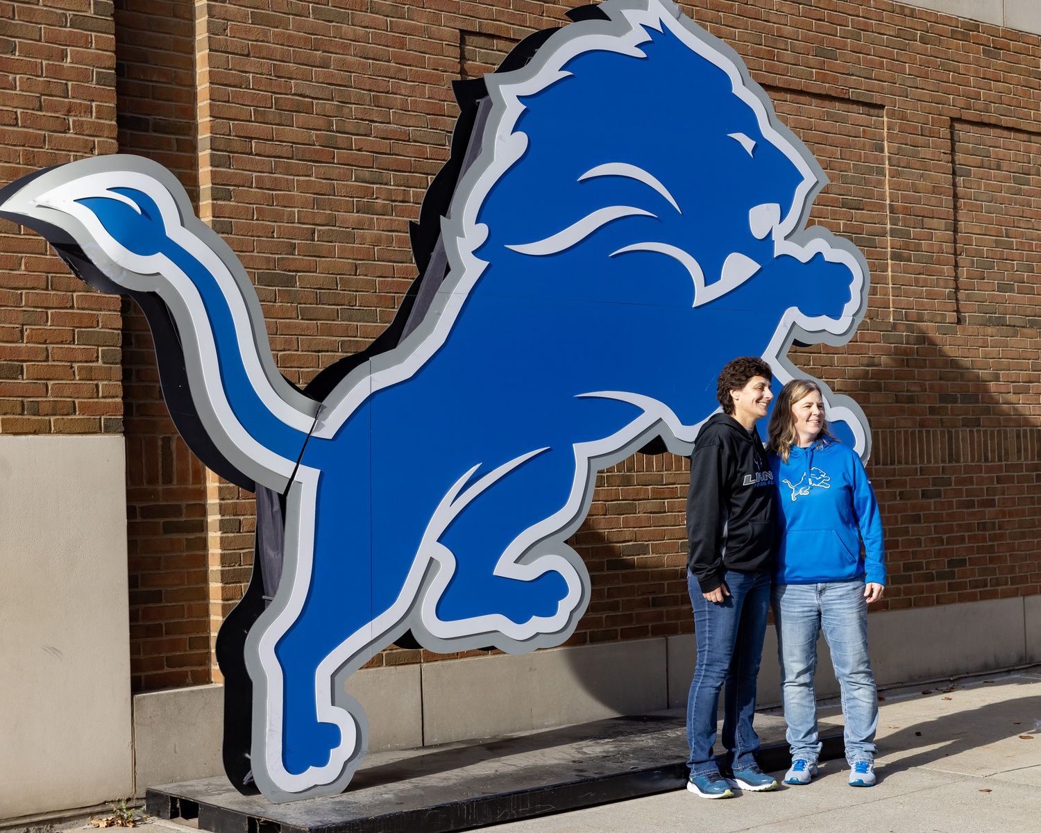 Fans take a picture in front of the Detroit Lions logo outside of Ford Field before the game against the Miami Dolphins.