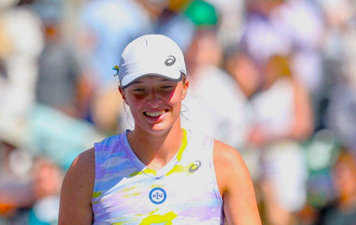 Iga Swiatek of Poland smiles as she walks back to pick up her racket after winning during the WTA singles final at the BNP Paribas Open at the Indian Wells Tennis Garden in Indian Wells, Calif., Sunday, March 20, 2022.