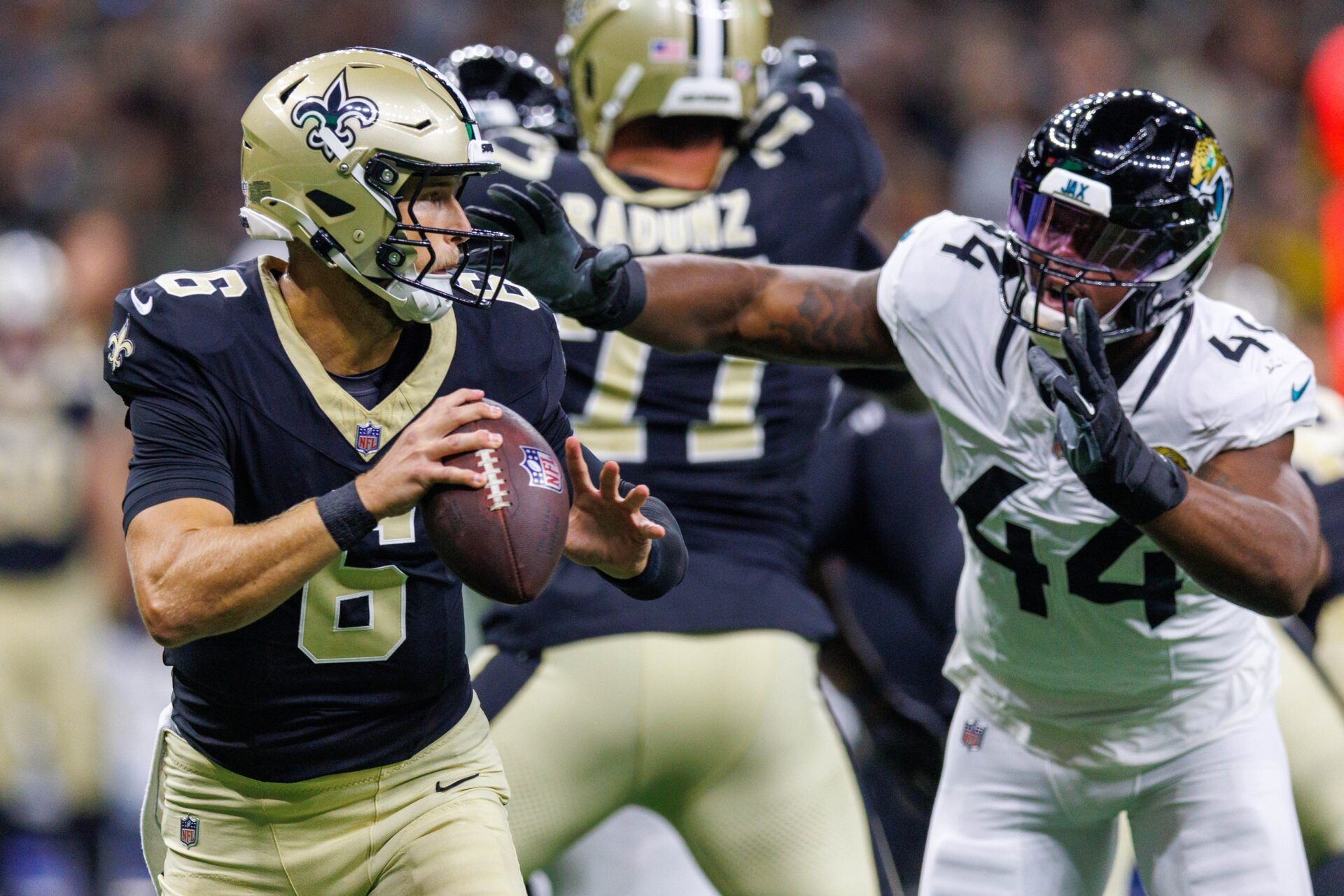 New Orleans Saints quarterback Tyler Shough (6) is chased out the pocket by Jacksonville Jaguars defensive end Travon Walker (44) during the first half at Caesars Superdome.