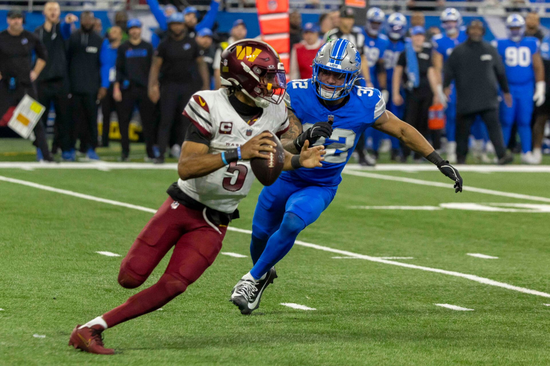 Washington Commanders quarterback Jayden Daniels (5) looks to pass defended by Detroit Lions defensive back Brian Branch (32) during the second half at Ford Field.