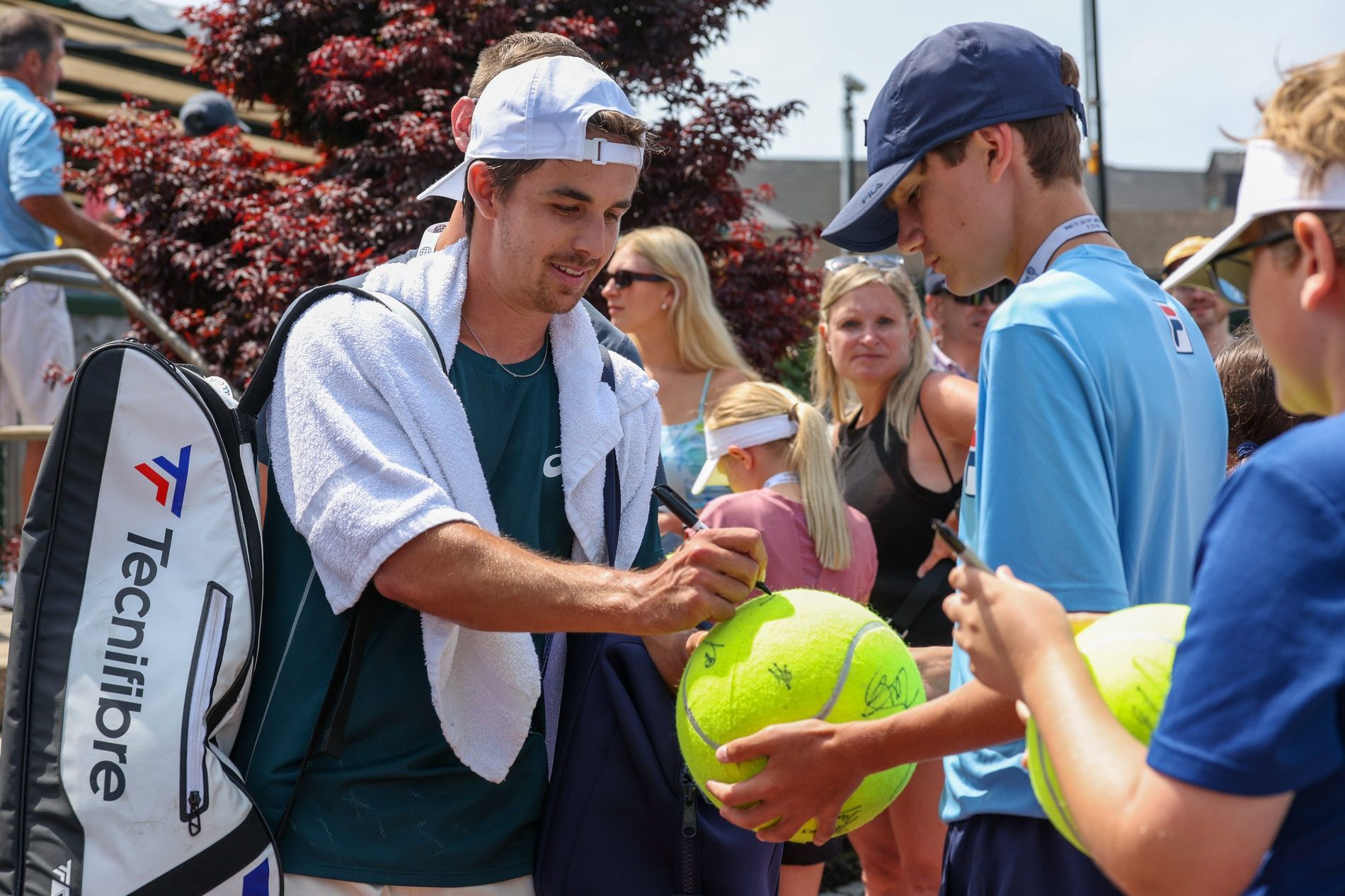 Zachary Svajda signs a giant tennis ball for a fan at the Hall of Fame Open on Saturday, July 12.