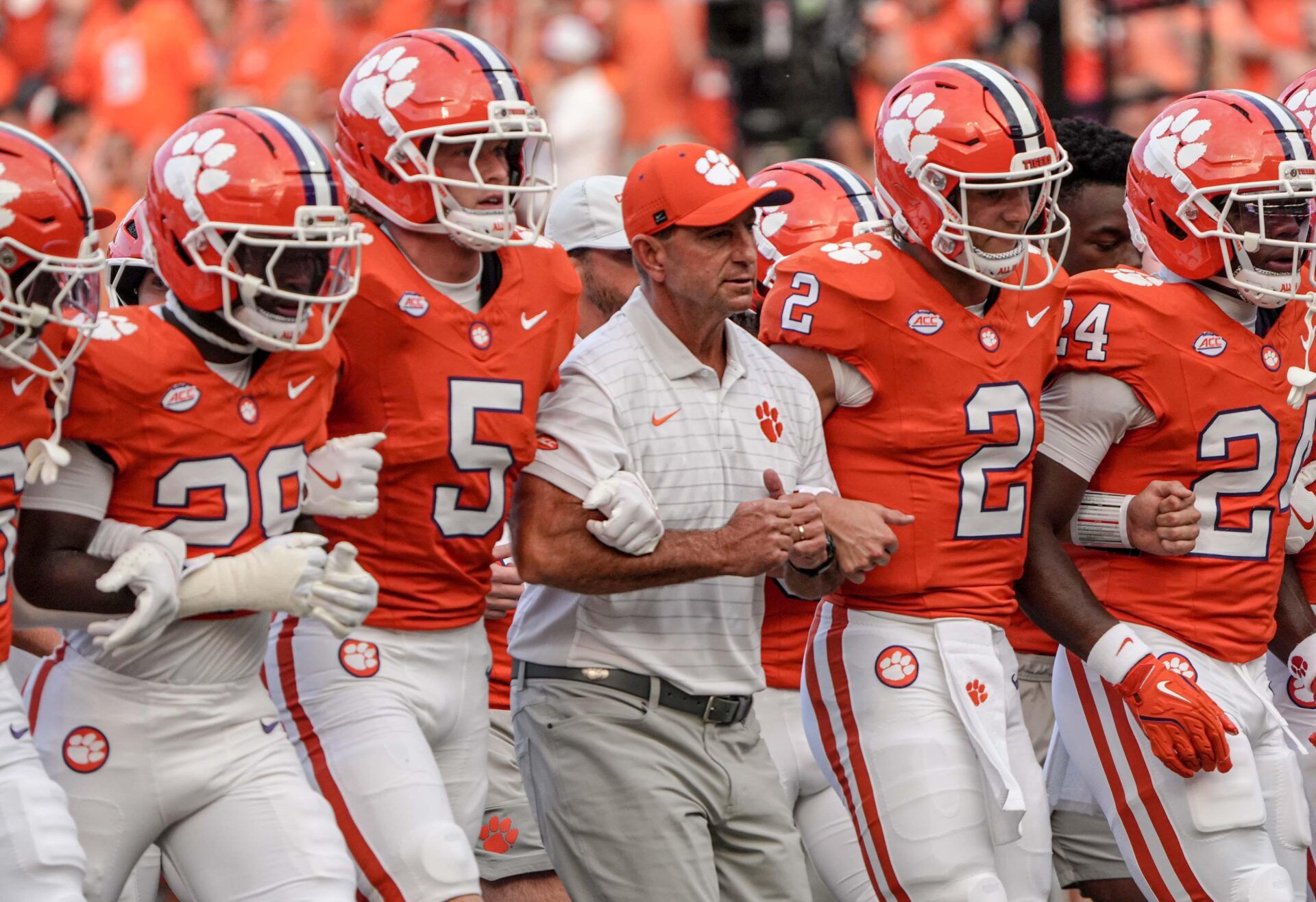 Clemson head coach Dabo Swinney arm-in-arm with defensive back Ronan Hanafin (5) and quarterback Cade Klubnik (2) and teammates during the “Walk of Champions” march to the end zone, before the game with Clemson and Louisiana State University at Memorial Stadium in Clemson, S.C. Saturday, August 30, 2025.