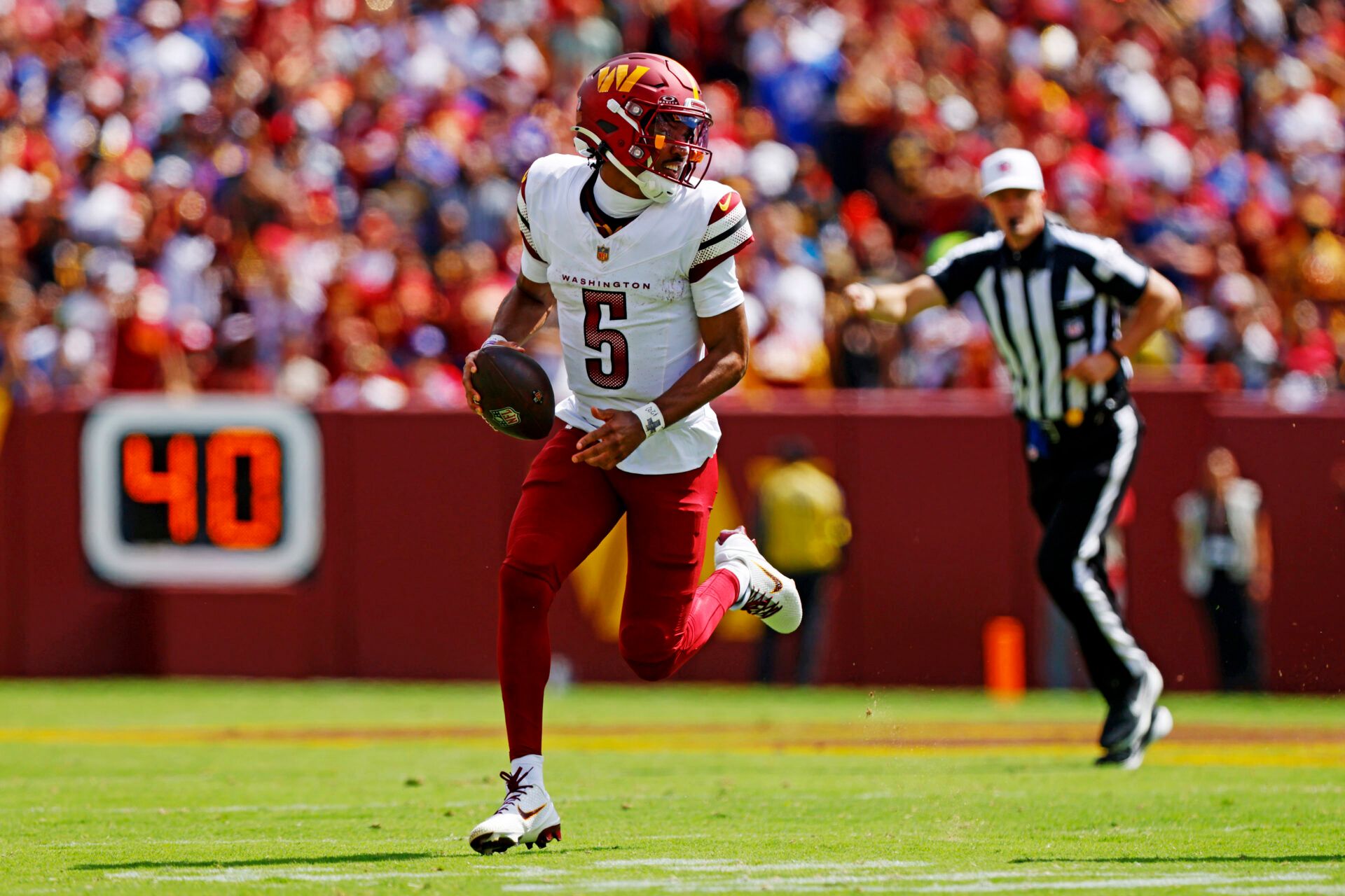 Washington Commanders quarterback Jayden Daniels (5) runs the ball against New York Giants linebacker Brian Burns (0) during the second quarter at Northwest Stadium.