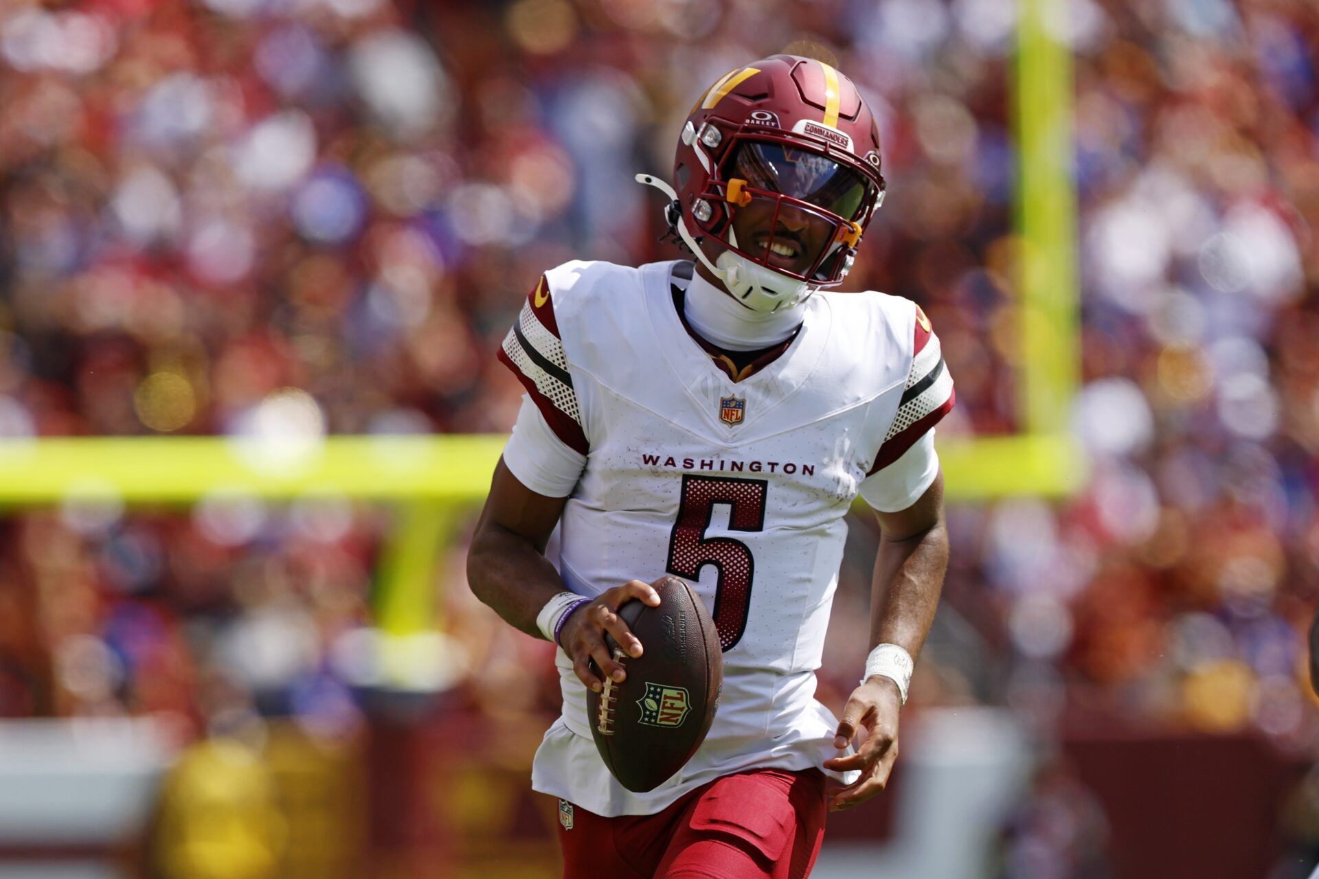 Washington Commanders quarterback Jayden Daniels (5) runs the ball against New York Giants linebacker Brian Burns (0) during the second quarter at Northwest Stadium.