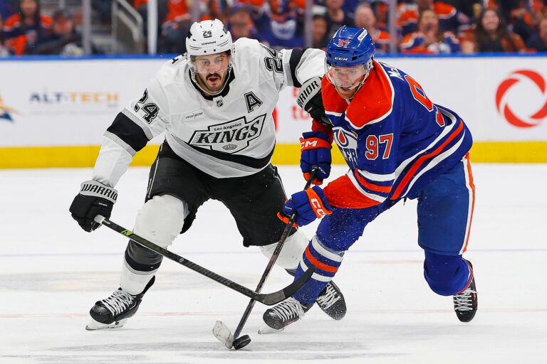 Los Angeles Kings forward Phillip Danault (24) tries to knock the puck away from Edmonton Oilers forward Connor McDavid (97) during the second period in game six of the first round of the 2025 Stanley Cup Playoffs at Rogers Place.