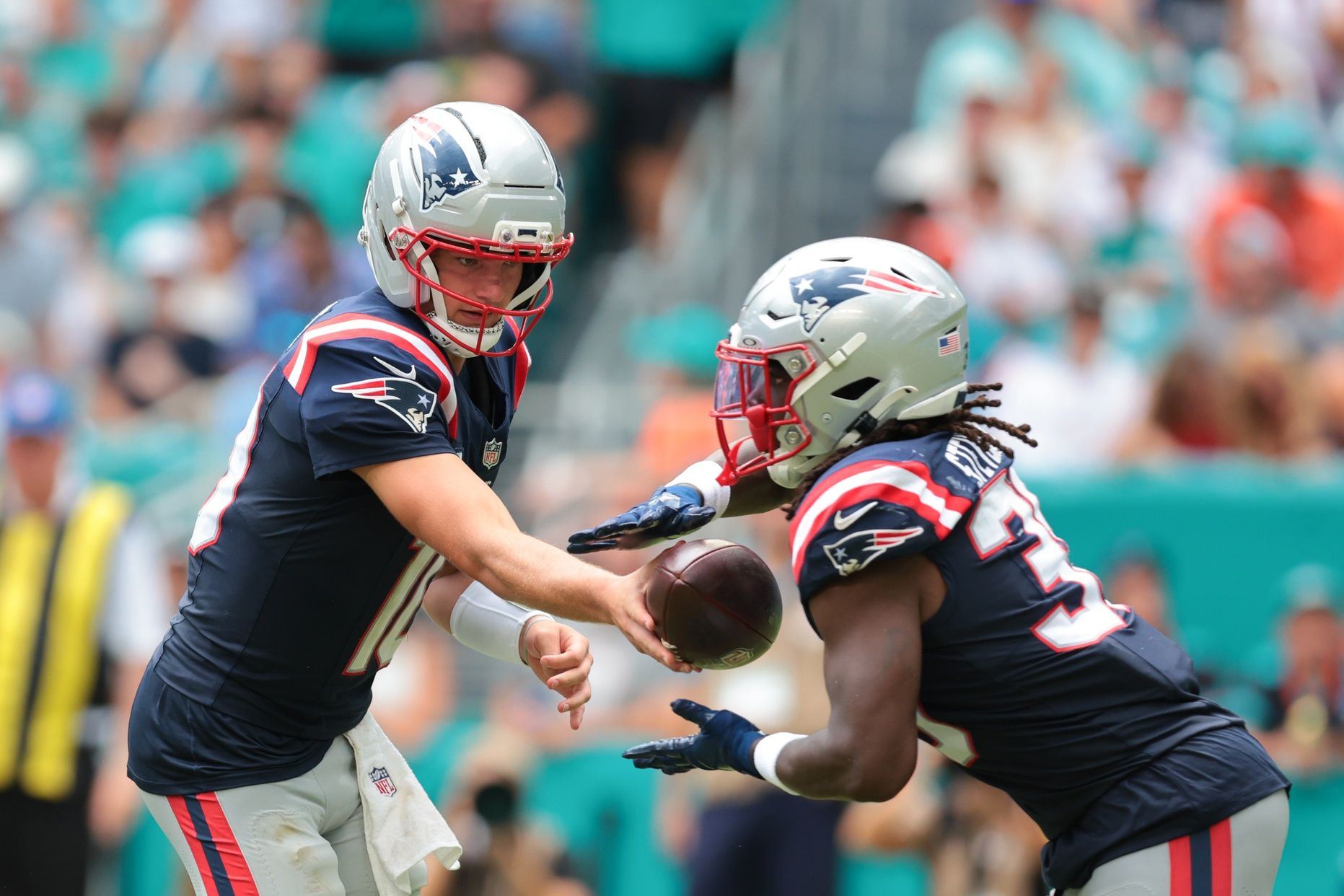 New England Patriots running back Rhamondre Stevenson (38) takes a handoff from quarterback Drake Maye (10) against the Miami Dolphins during the third quarter at Hard Rock Stadium.