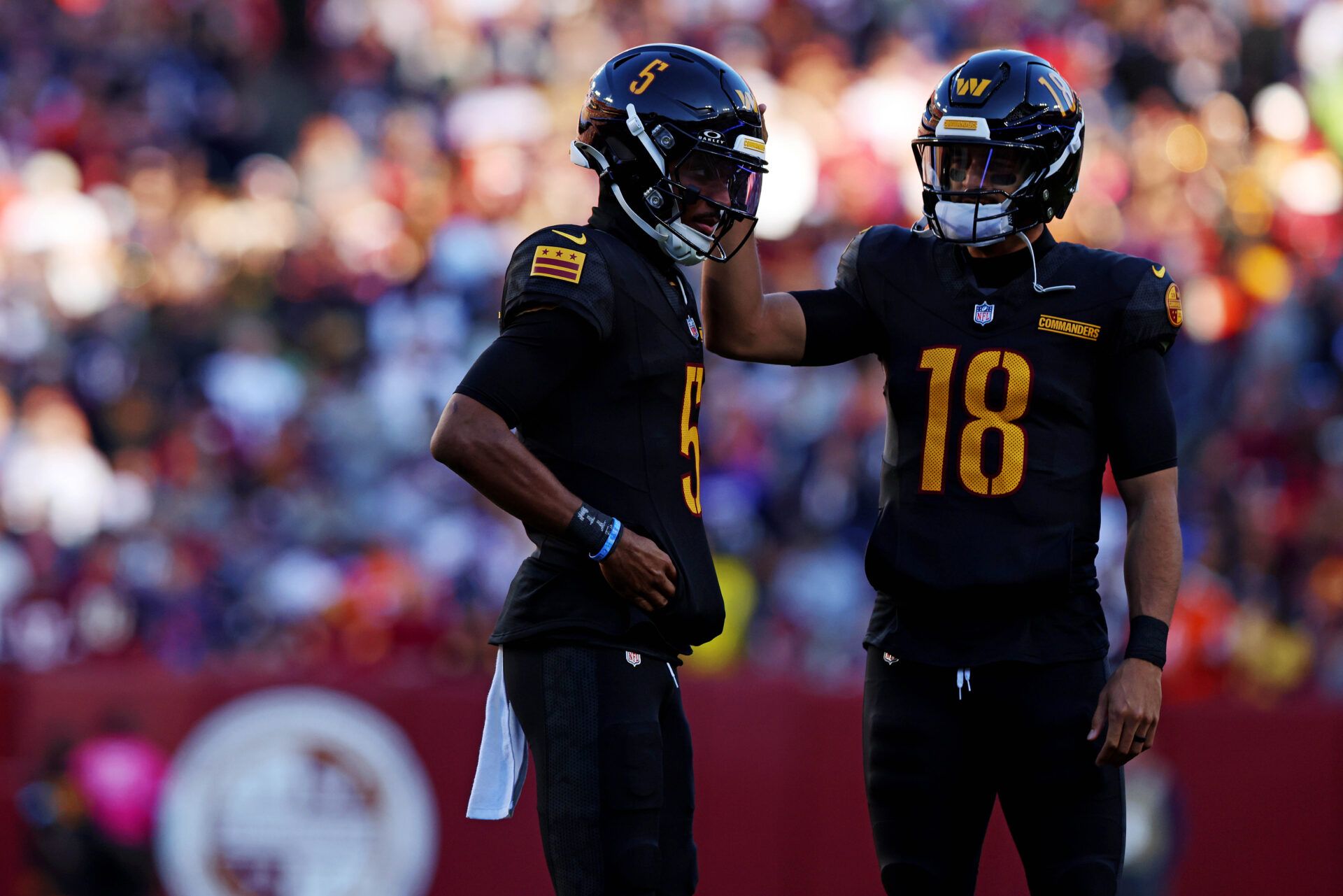 Washington Commanders quarterback Jayden Daniels (5) and quarterback Marcus Mariota (18) talk to each other during the first half against the Chicago Bears at Commanders Field.