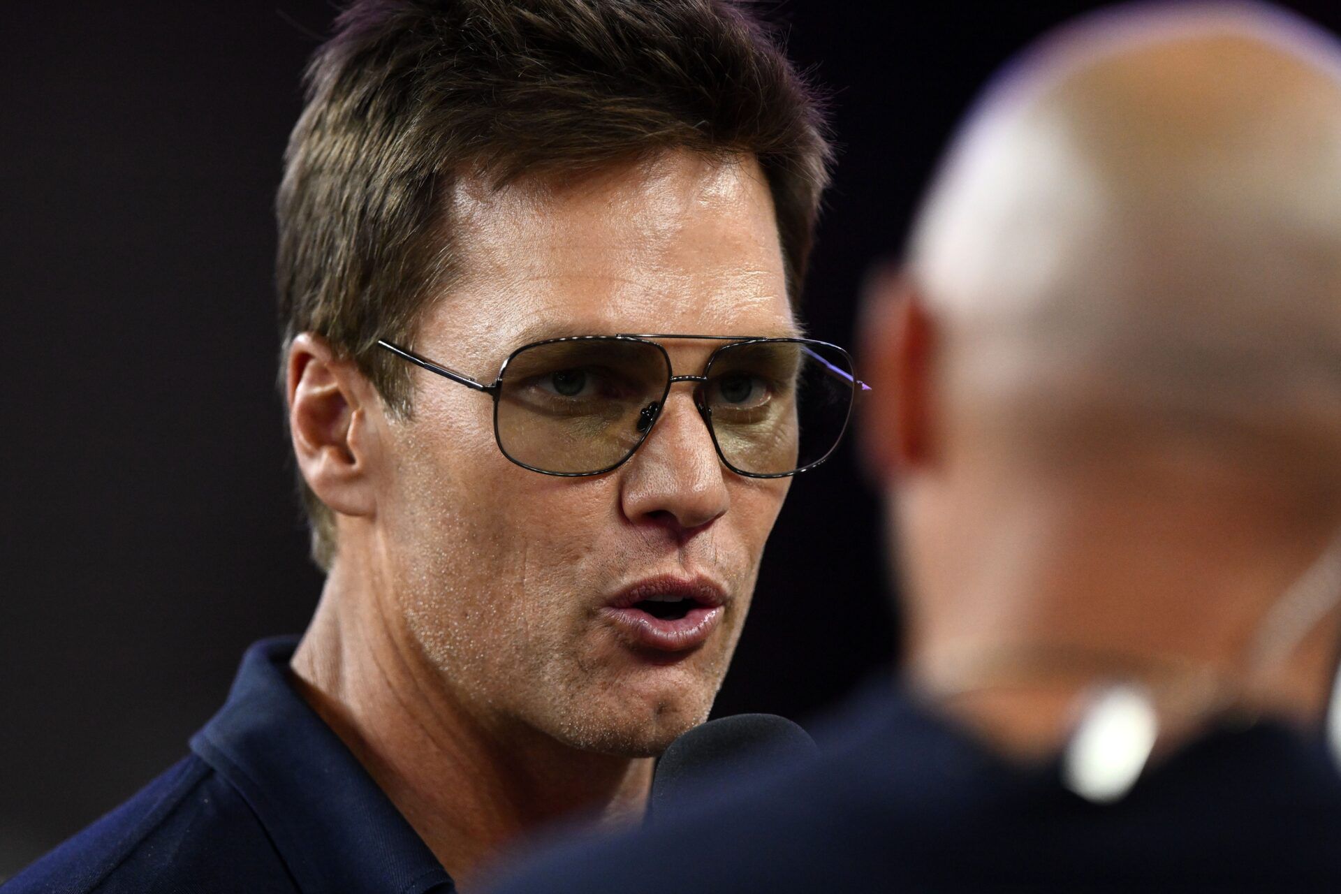 Retired Hall of Fame New England Patriot player Tom Brady talks with Brian Hoyer during the first half of a game against the Washington Commanders at Gillette Stadium.