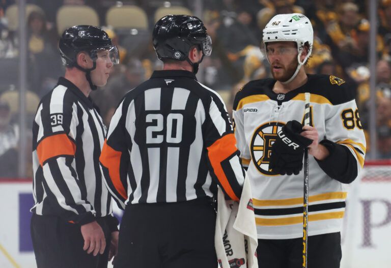 NHL  referees Brandon Blandina (63) and Mitch Dunning (20) talk  with Boston Bruins right wing David Pastrnak (88) against the Pittsburgh Penguins during the third period at PPG Paints Arena.