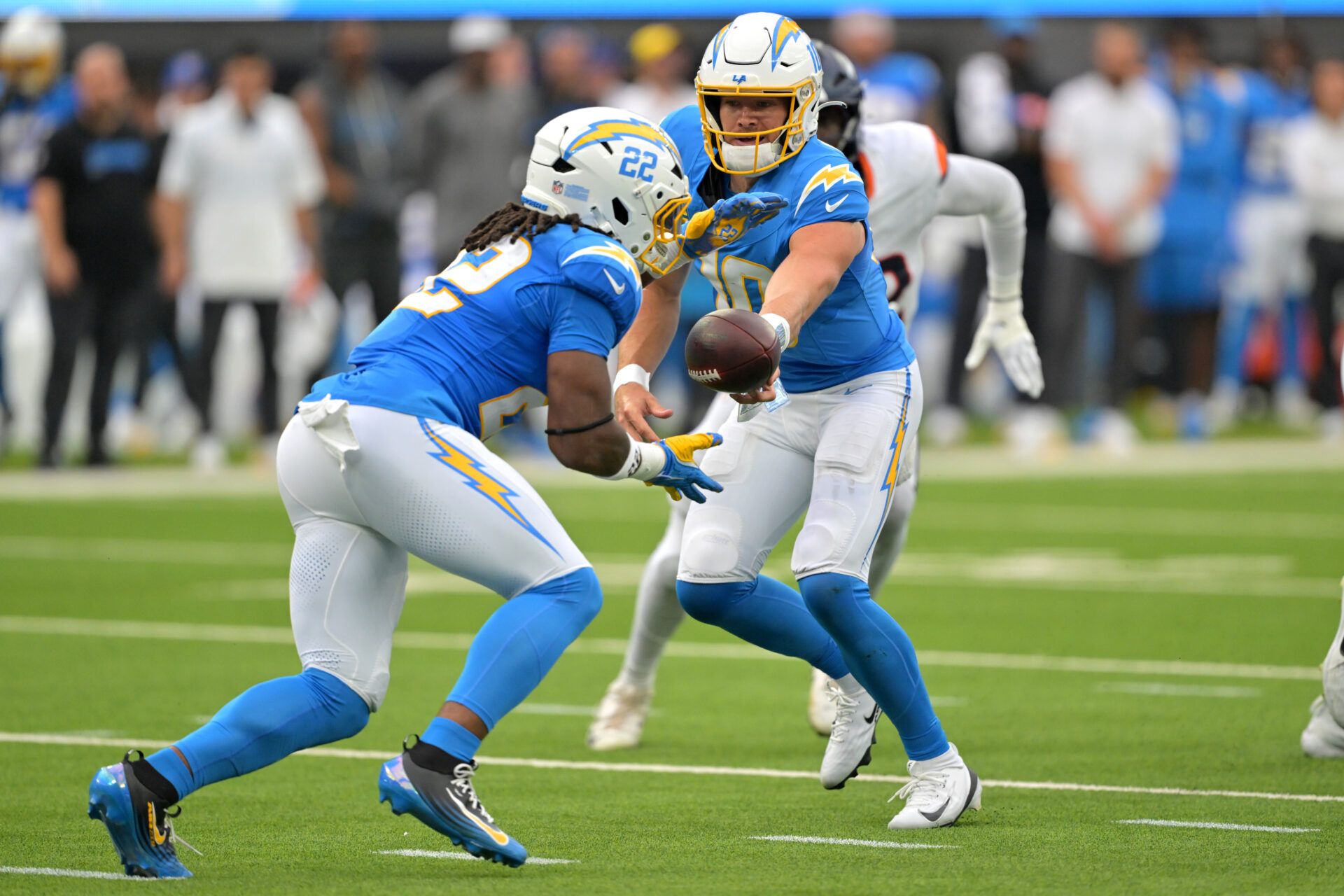 Los Angeles Chargers running back Najee Harris (22) takes a hand off from quarterback Justin Herbert (10) and runs for a first down in the first quarter against the Denver Broncos at SoFi Stadium.