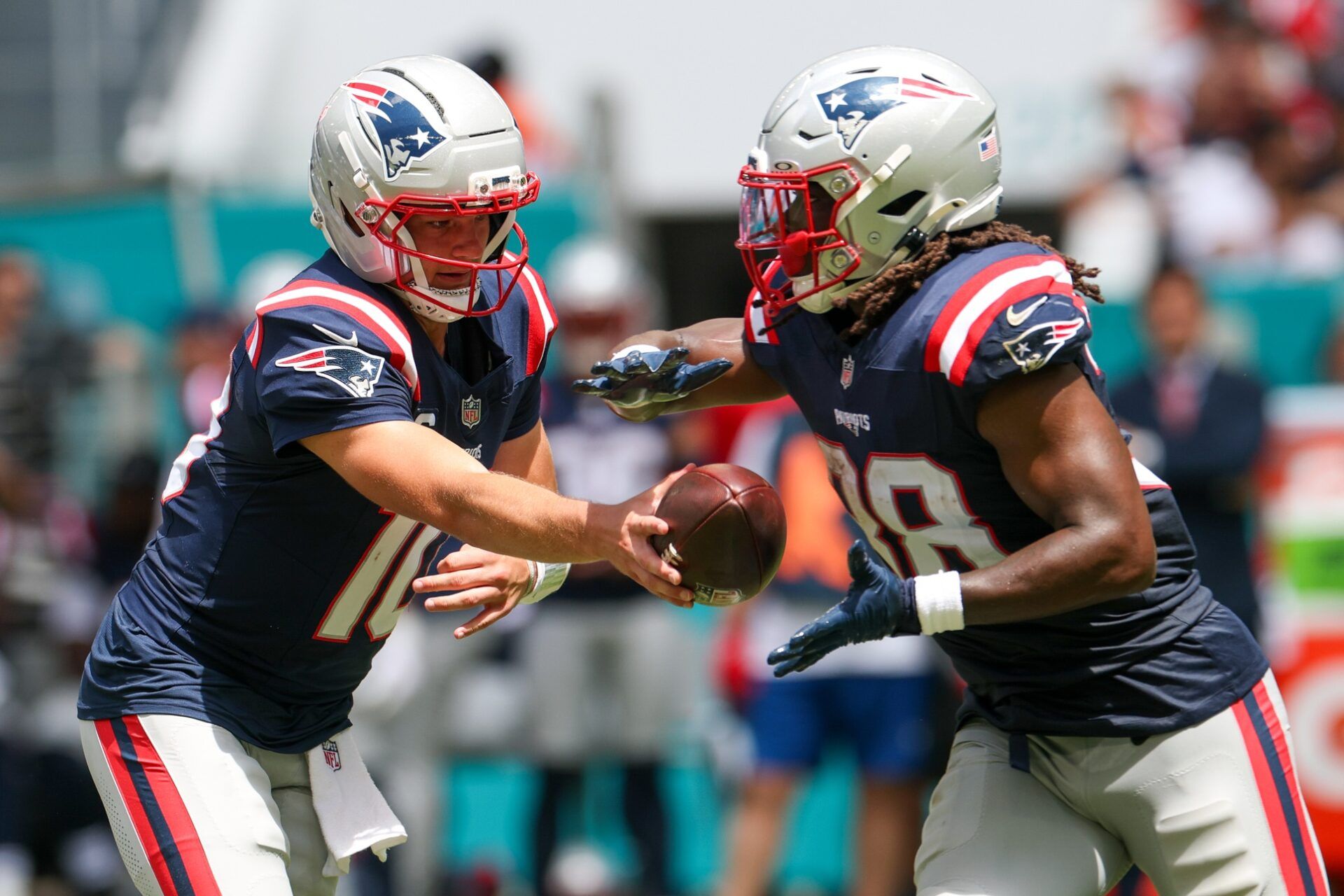 New England Patriots quarterback Drake Maye (10) hands off to running back Rhamondre Stevenson (38) against the Miami Dolphins in the first quarter at Hard Rock Stadium.