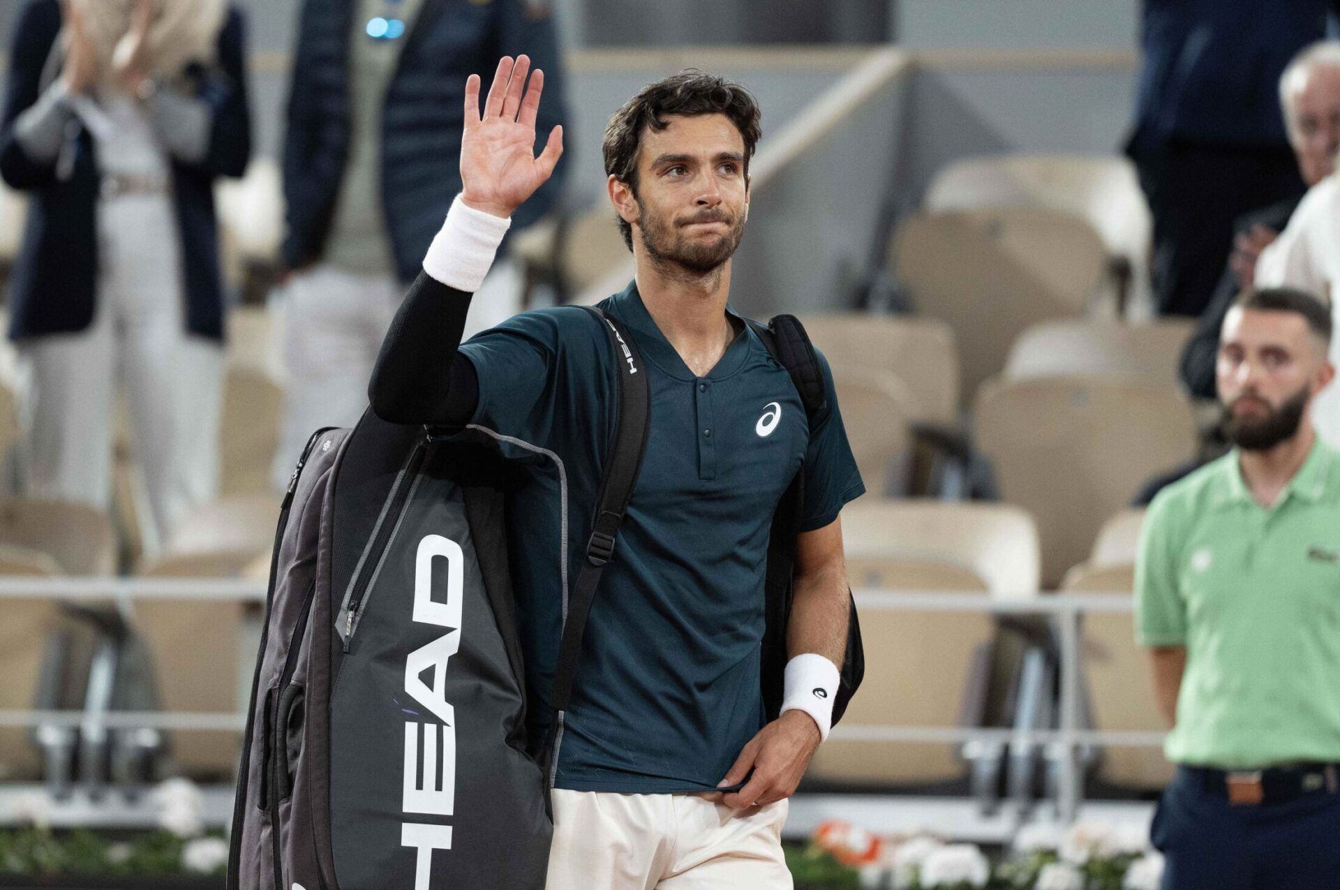 Lorenzo Musetti of Italy waves as he leaves the court after retiring in the fourth set of his match against Carlos Alcaraz of Spain on day 13 at Roland Garros Stadium.