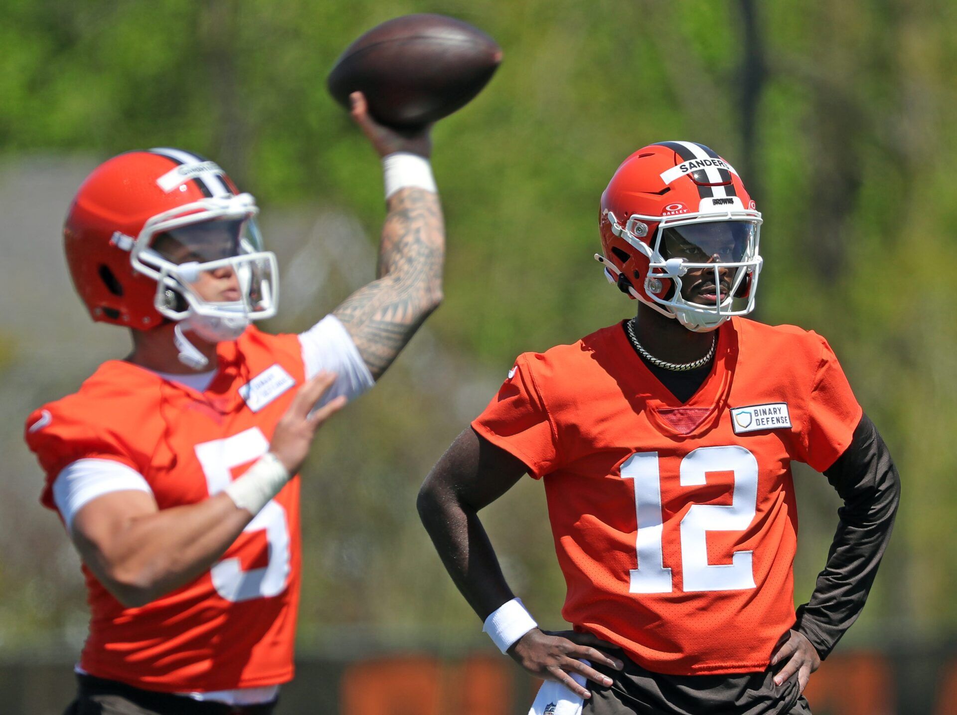 Cleveland Browns quarterback Shedeur Sanders (12) watches as quarterback Dillon Gabriel (5) throws during NFL rookie minicamp at the Cleveland Browns training facility on Friday, May 9, 2025, in Berea, Ohio.
