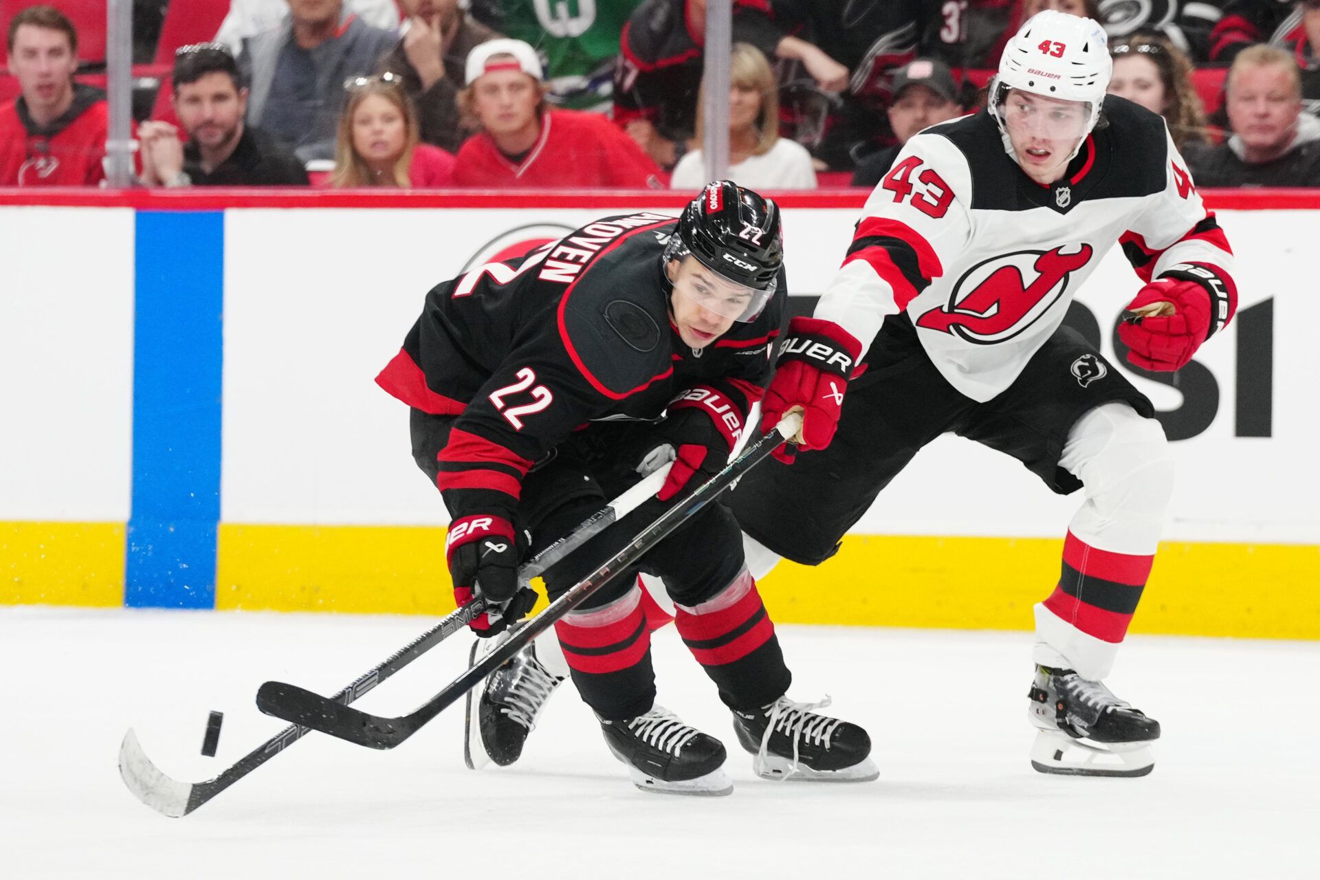 Carolina Hurricanes center Logan Stankoven (22) battles for the puck against New Jersey Devils defenseman Luke Hughes (43) during the third period of game one of the first round of the 2025 Stanley Cup Playoffs at Lenovo Center.