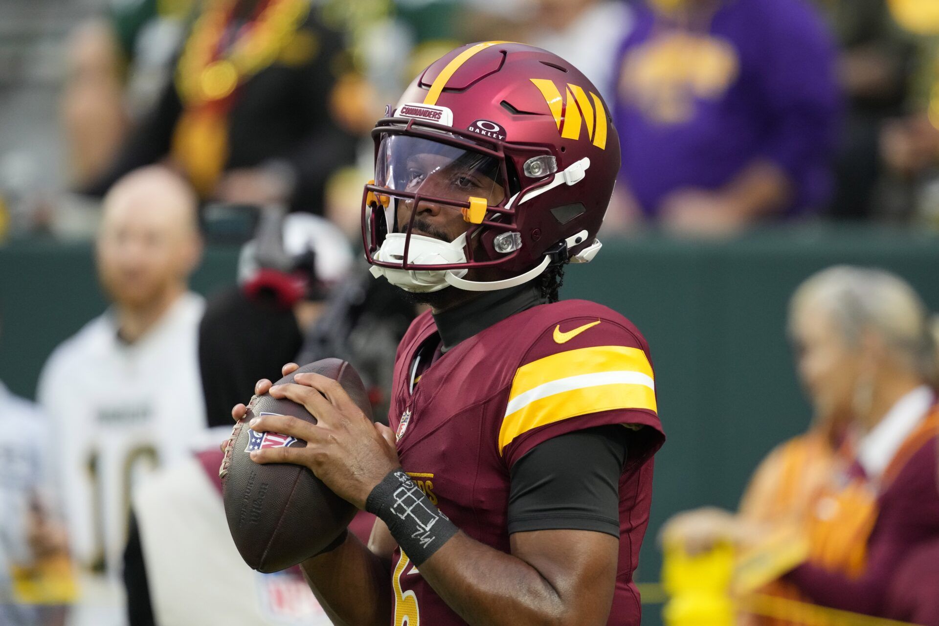 Washington Commanders quarterback Jayden Daniels (5) warms up before a game against the Green Bay Packers at Lambeau Field.