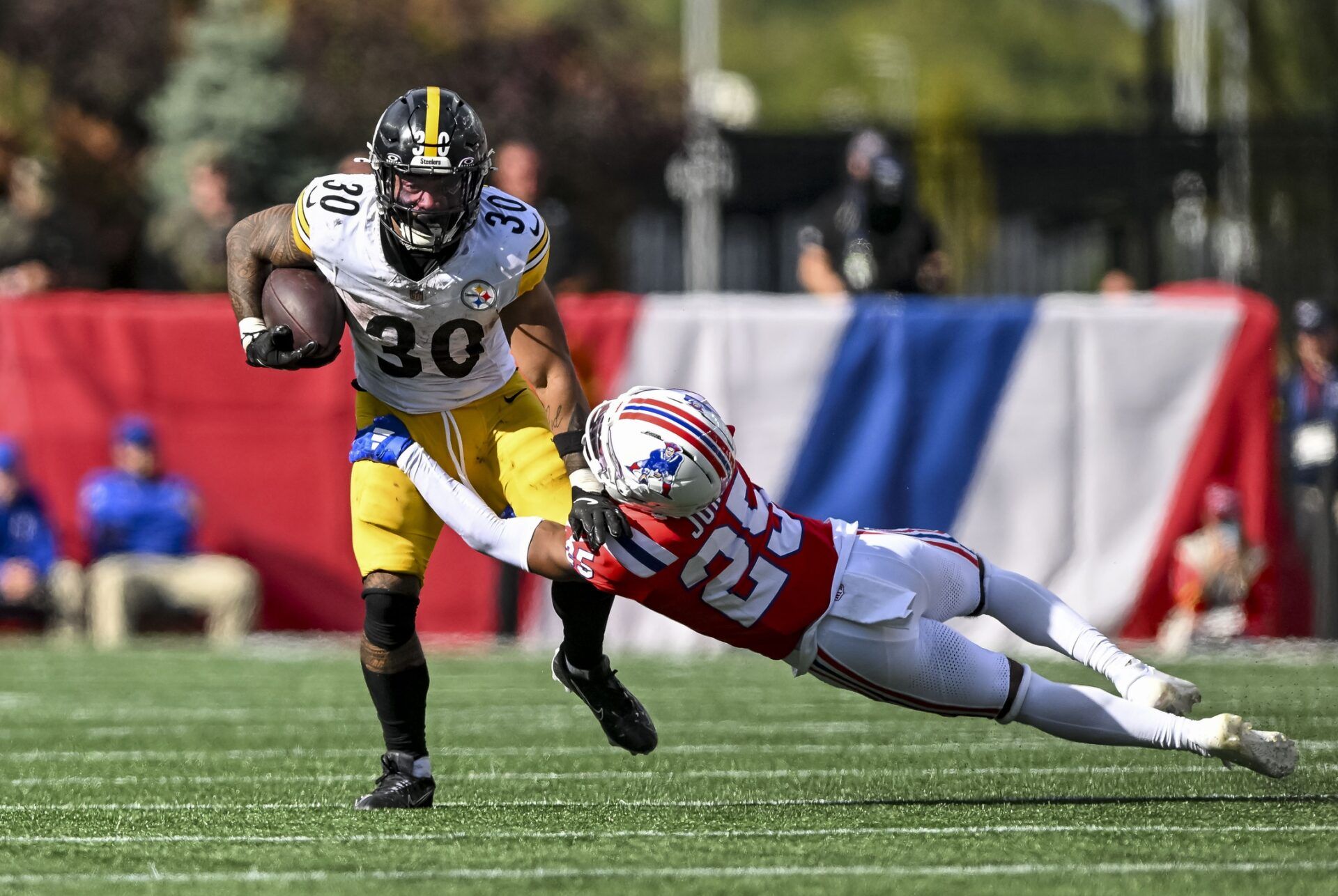 New England Patriots cornerback Marcus Jones (25) attempts to tackle Pittsburgh Steelers running back Jaylen Warren (30) during the fourth quarter at Gillette Stadium.
