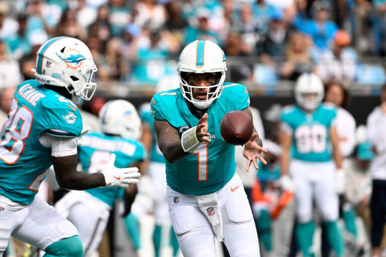 Miami Dolphins quarterback Tua Tagovailoa (1) pitches the ball to running back De'Von Achane (28) in the third quarter at Bank of America Stadium.