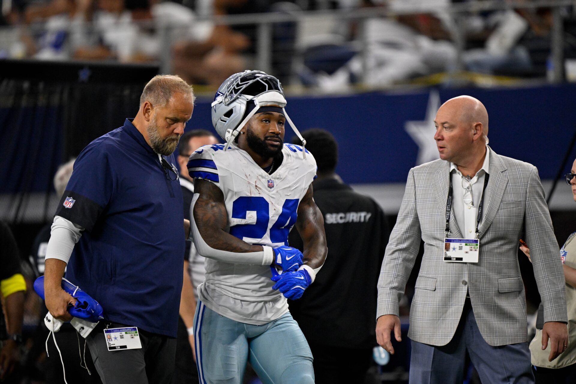 Dallas Cowboys running back Miles Sanders (24) walks off the field with team staff during the game between the Dallas Cowboys and the Green Bay Packers at AT&T Stadium.