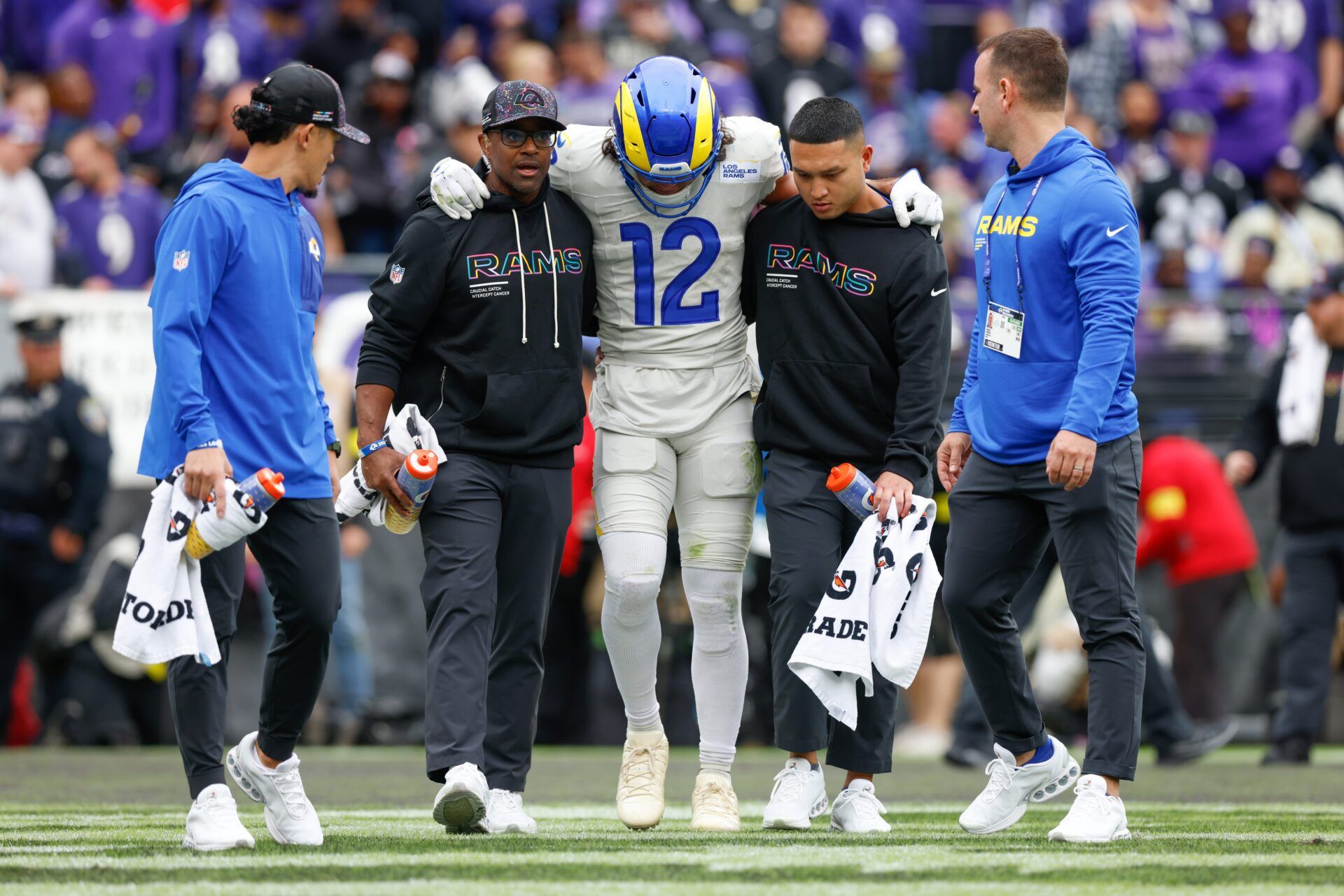Los Angeles Rams wide receiver Puka Nacua (12) is helped off the field by trainers during the second quarter of the game against the Baltimore Ravens at M&T Bank Stadium.