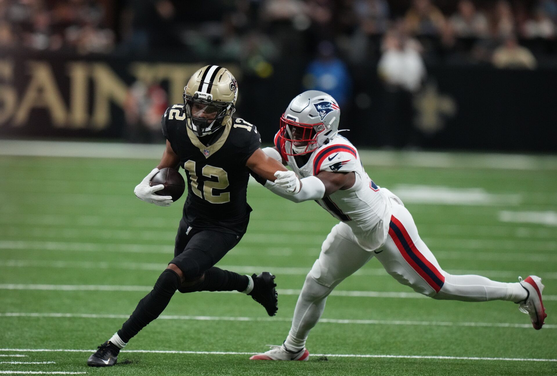 New Orleans Saints wide receiver Chris Olave (12) runs for a gain past New England Patriots safety Craig Woodson (31) during the second quarter at Caesars Superdome.