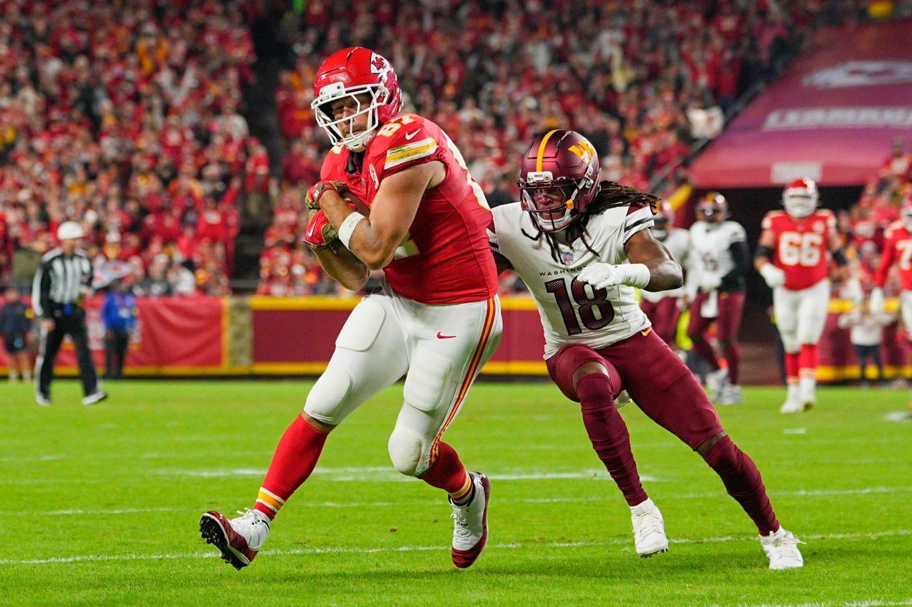 Kansas City Chiefs tight end Travis Kelce (87) carries the ball defended by Washington Commanders safety Tyler Owens (18) during the second quarter of the game at GEHA Field at Arrowhead Stadium.
