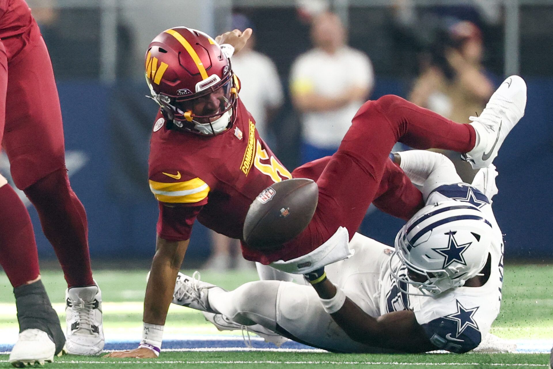 Washington Commanders quarterback Jayden Daniels (5) fumbles the ball defended by Dallas Cowboys linebacker Shemar James (50) during the third quarter of the game at AT&T Stadium.