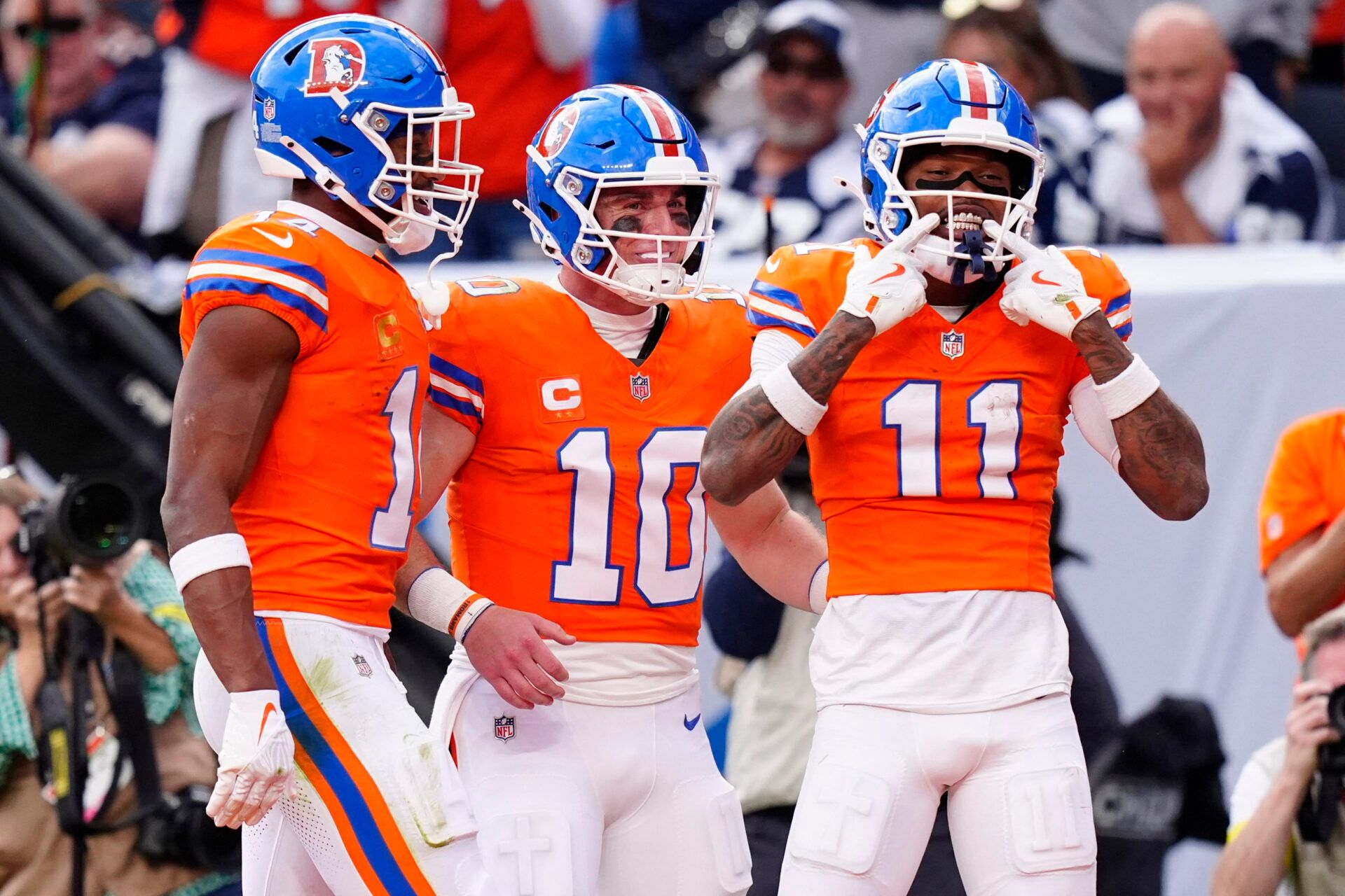 Denver Broncos wide receiver Troy Franklin (11) celebrates with wide receiver Courtland Sutton (14) and quarterback Bo Nix (10) after scoring a touchdown against the Dallas Cowboys in the fourth quarter at Empower Field at Mile High.
