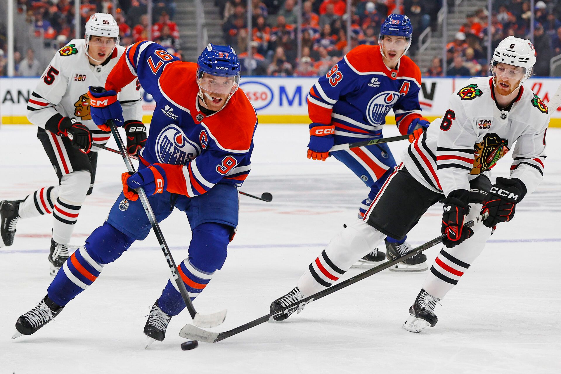 Edmonton Oilers forward Connor McDavid (97) and Chicago Blackhawks defensemen Sam Rinzel (6) battle for a loose puck during the third period at Rogers Place.