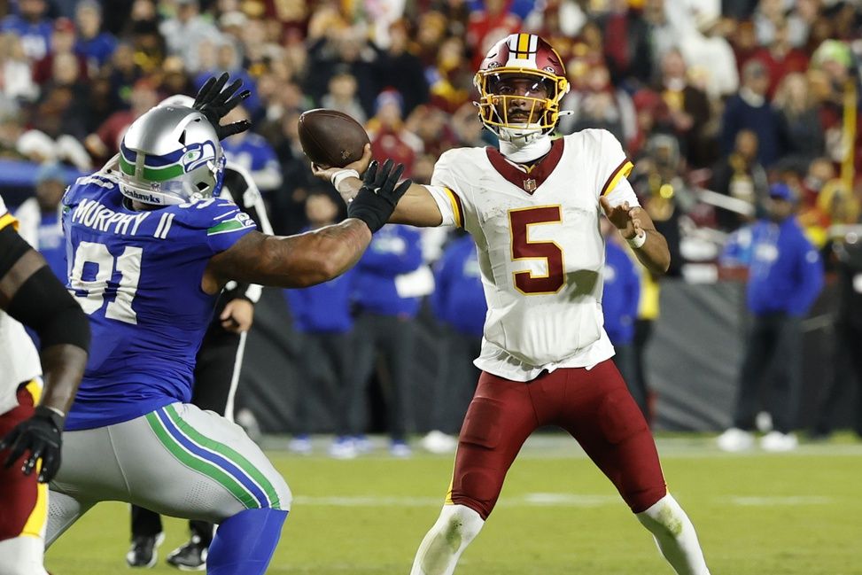 Washington Commanders quarterback Jayden Daniels (5) passes the ball as Seattle Seahawks defensive tackle Byron Murphy II (91) chases in the second quarter at Northwest Stadium.