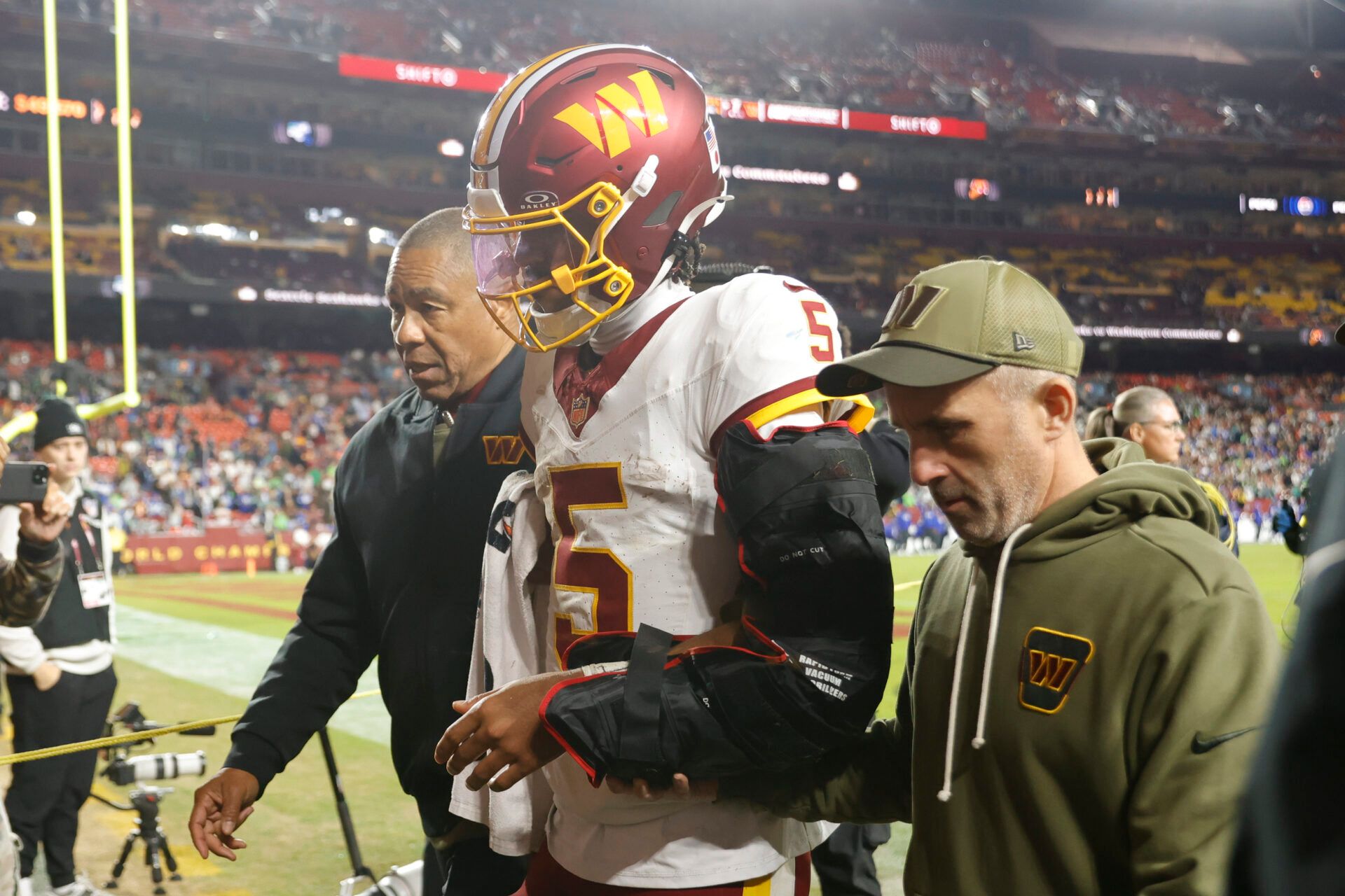 Washington Commanders quarterback Jayden Daniels (5) is helped off the field after an injury during the second half against the Seattle Seahawks at Northwest Stadium.