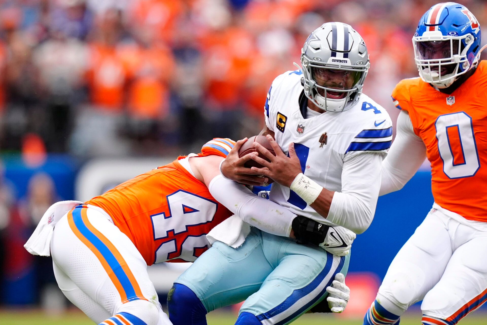 Denver Broncos linebacker Alex Singleton (49) tackles Dallas Cowboys quarterback Dak Prescott (4) in the first half at Empower Field at Mile High.