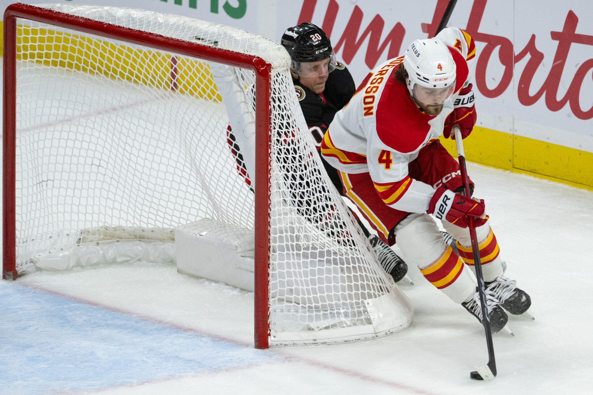 Calgary Flames defenseman Rasmus Andersson (4) skates with the puck in front of Ottawa Senators left wing Fabian Zetterlund (20) in the third period at the Canadian Tire Centre.