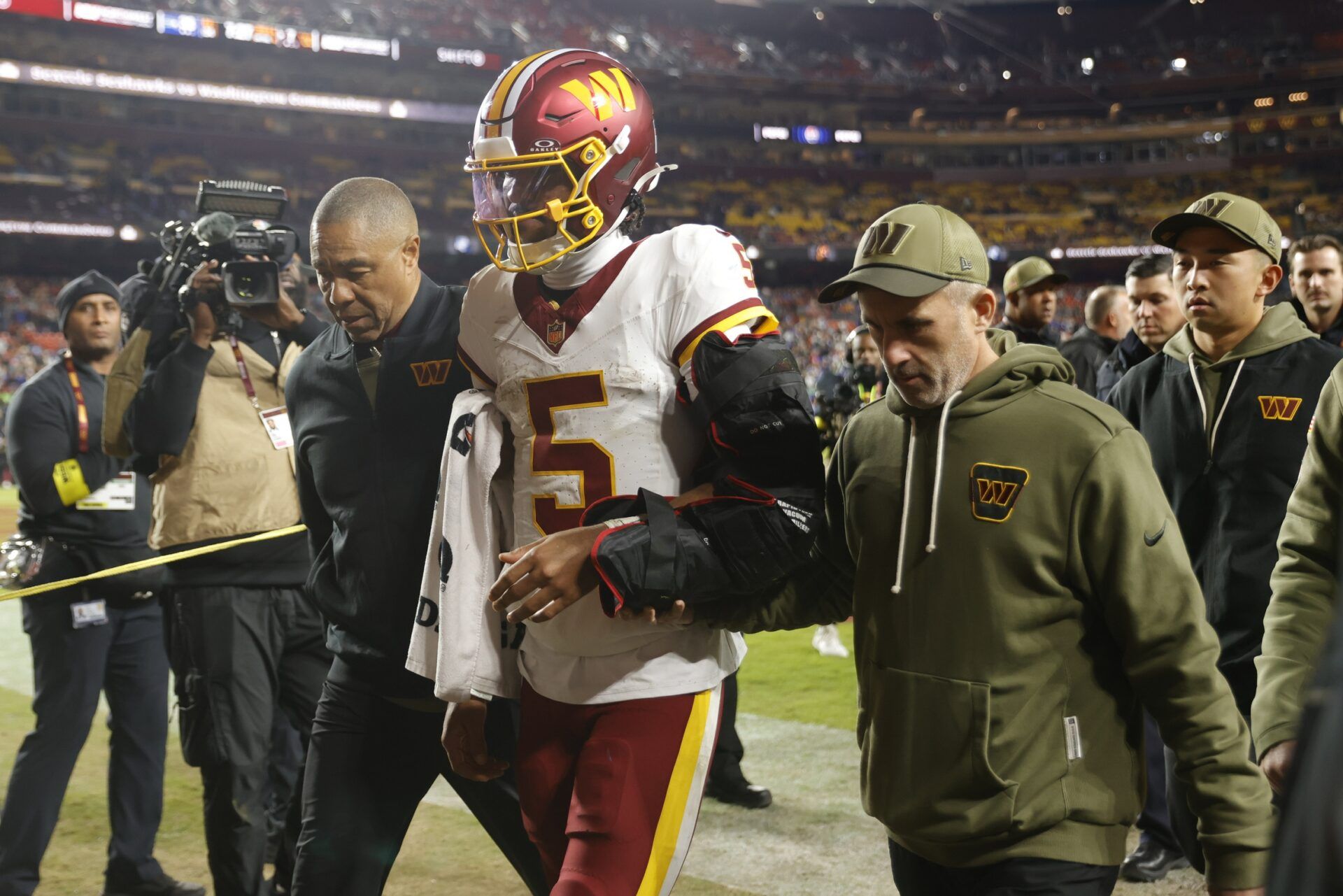 Washington Commanders quarterback Jayden Daniels (5) is helped off the field after an injury during the second half against the Seattle Seahawks at Northwest Stadium.
