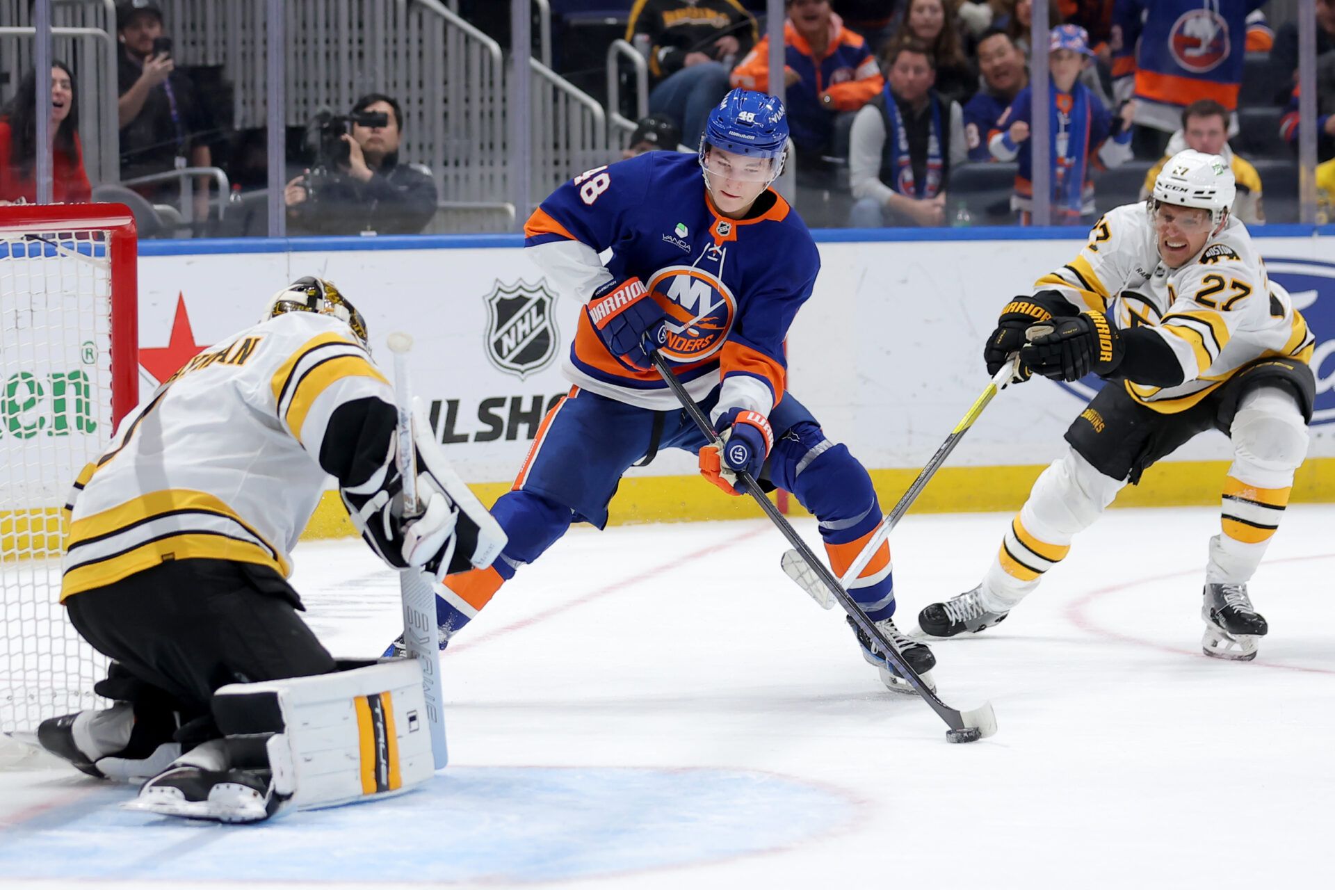 New York Islanders defenseman Matthew Schaefer (48) takes a shot against Boston Bruins goaltender Jeremy Swayman (1) and defenseman Hampus Lindholm (27) during overtime at UBS Arena.