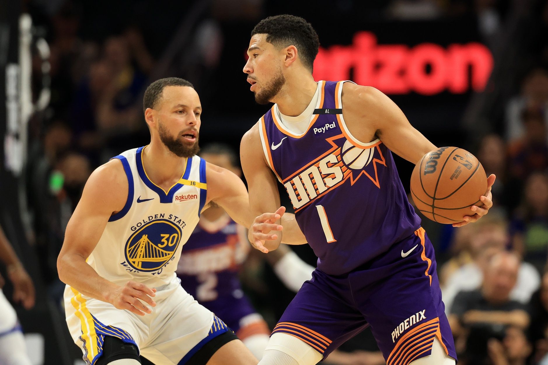 Phoenix Suns guard Devin Booker (1) dribbles the ball agisasnt Golden State Warriors guard Stephen Curry (30) during the first half at Footprint Center.