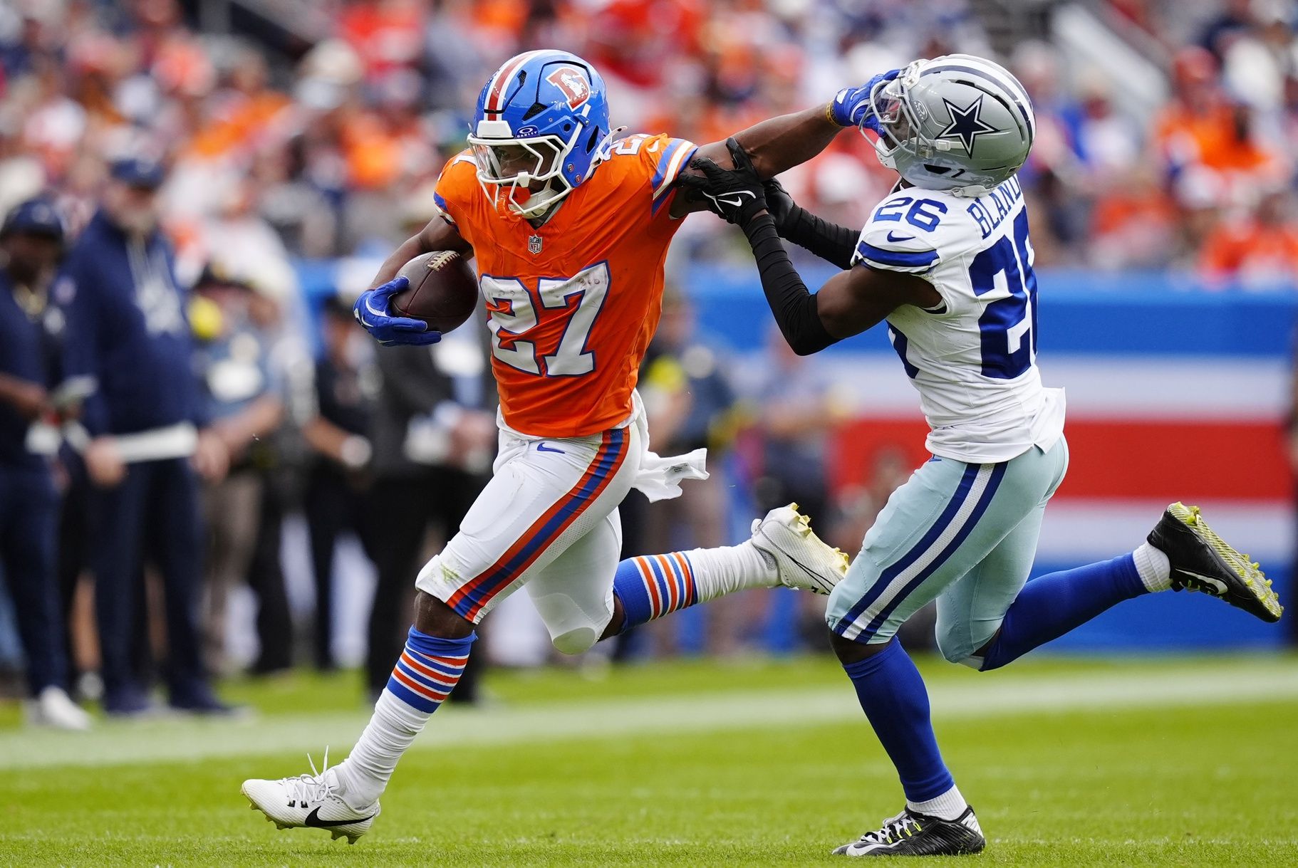 Denver Broncos running back J.K. Dobbins (27) runs against Dallas Cowboys cornerback DaRon Bland (26) in the first half at Empower Field at Mile High.