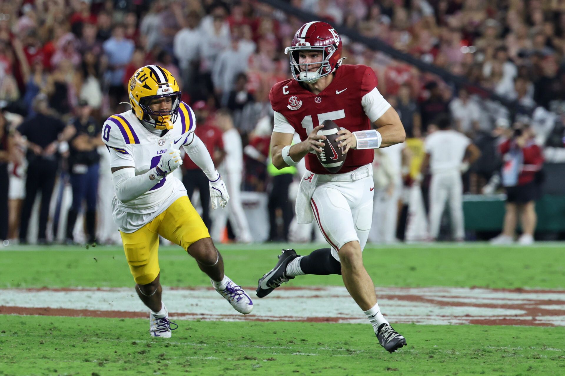Alabama Crimson Tide quarterback Ty Simpson (15) scrambles with the ball defended by Louisiana State Tigers safety Tamarcus Cooley (0) during the first quarter of the game at Saban Field at Bryant-Denny Stadium.