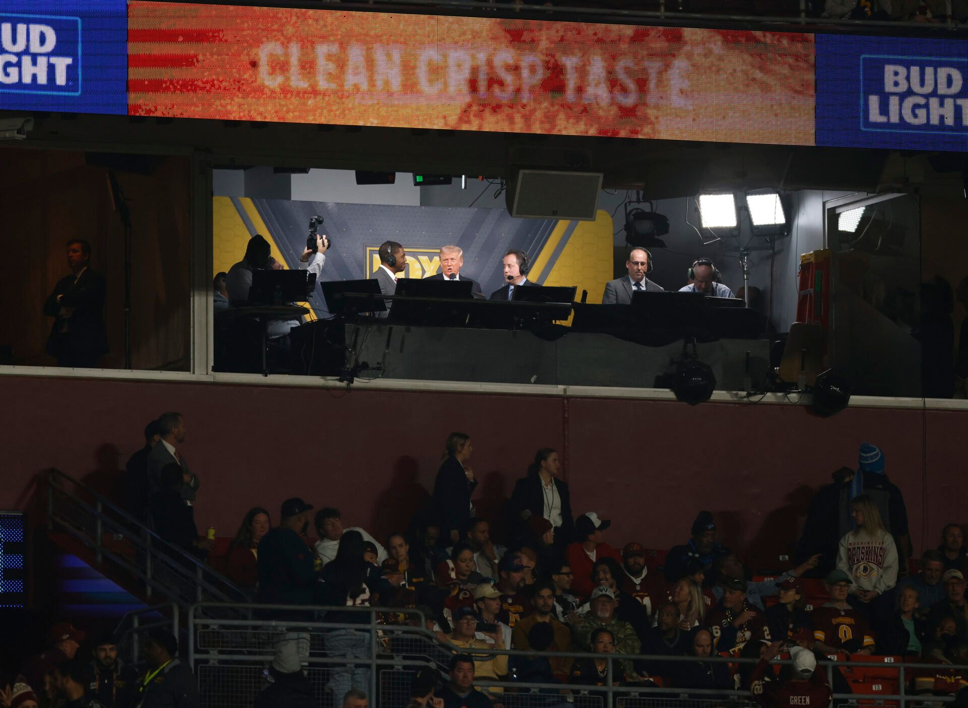 President Donald Trump is interviewed by Fox play-by-play announcer Kenny Albert and analyst Jonathan Vilma during the third quarter of a game between the Washington Commanders and the Detroit Lions at Northwest Stadium.