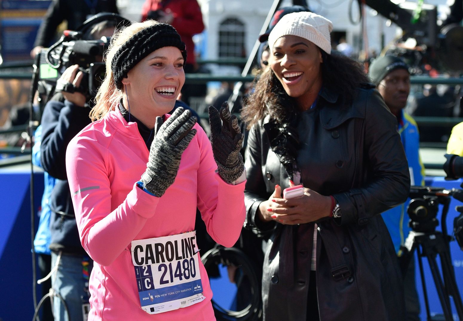 Tennis star Caroline Wozniacki reacts after crossing the finish line as Serena Williams looks on during the 2014 TCS New York City Marathon.