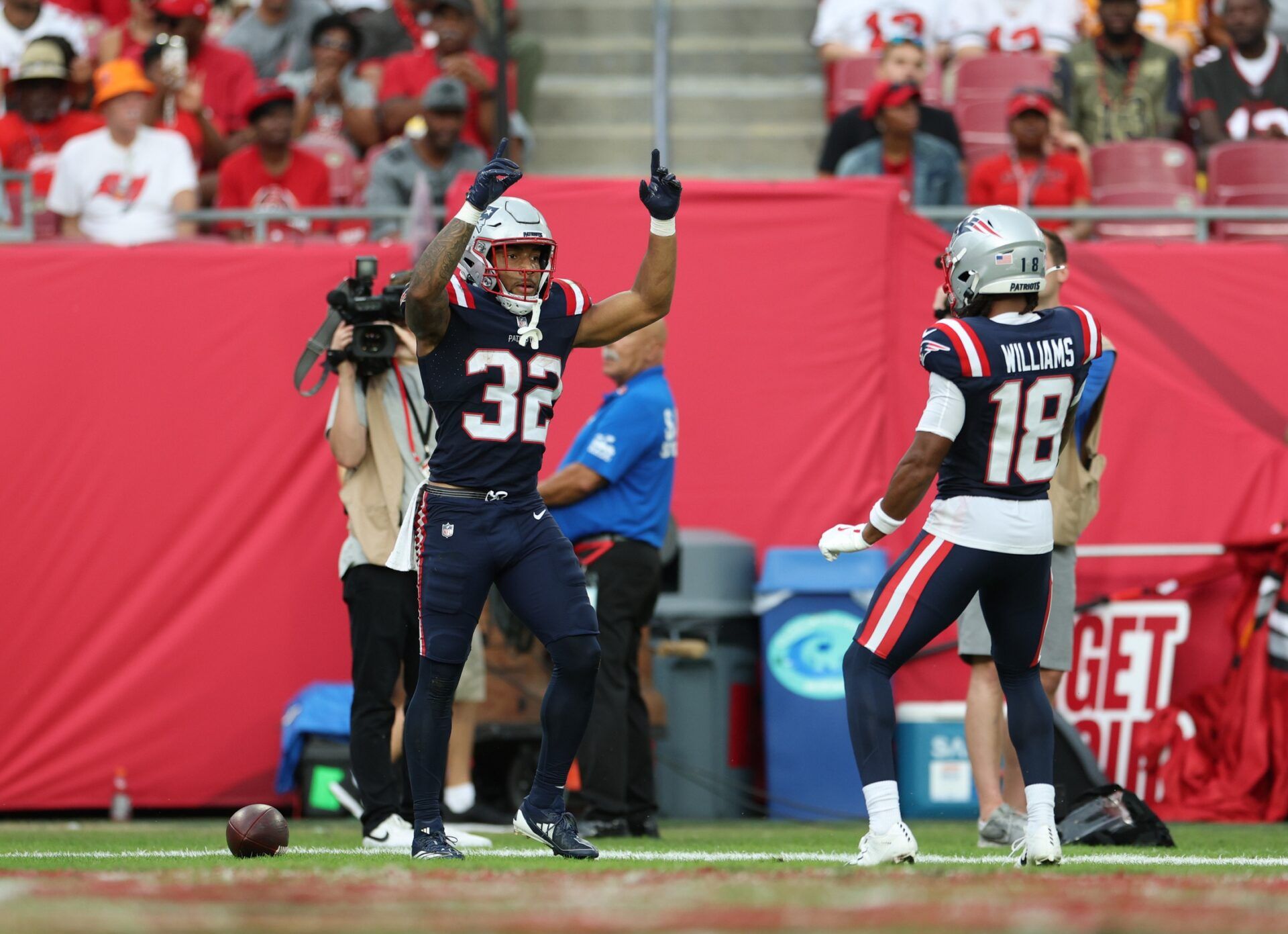 New England Patriots running back Treveyon Henderson (32) and wide receiver Kyle Williams (18) celebrate a touchdown during the third quarter against the Tampa Bay Buccaneers at Raymond James Stadium.