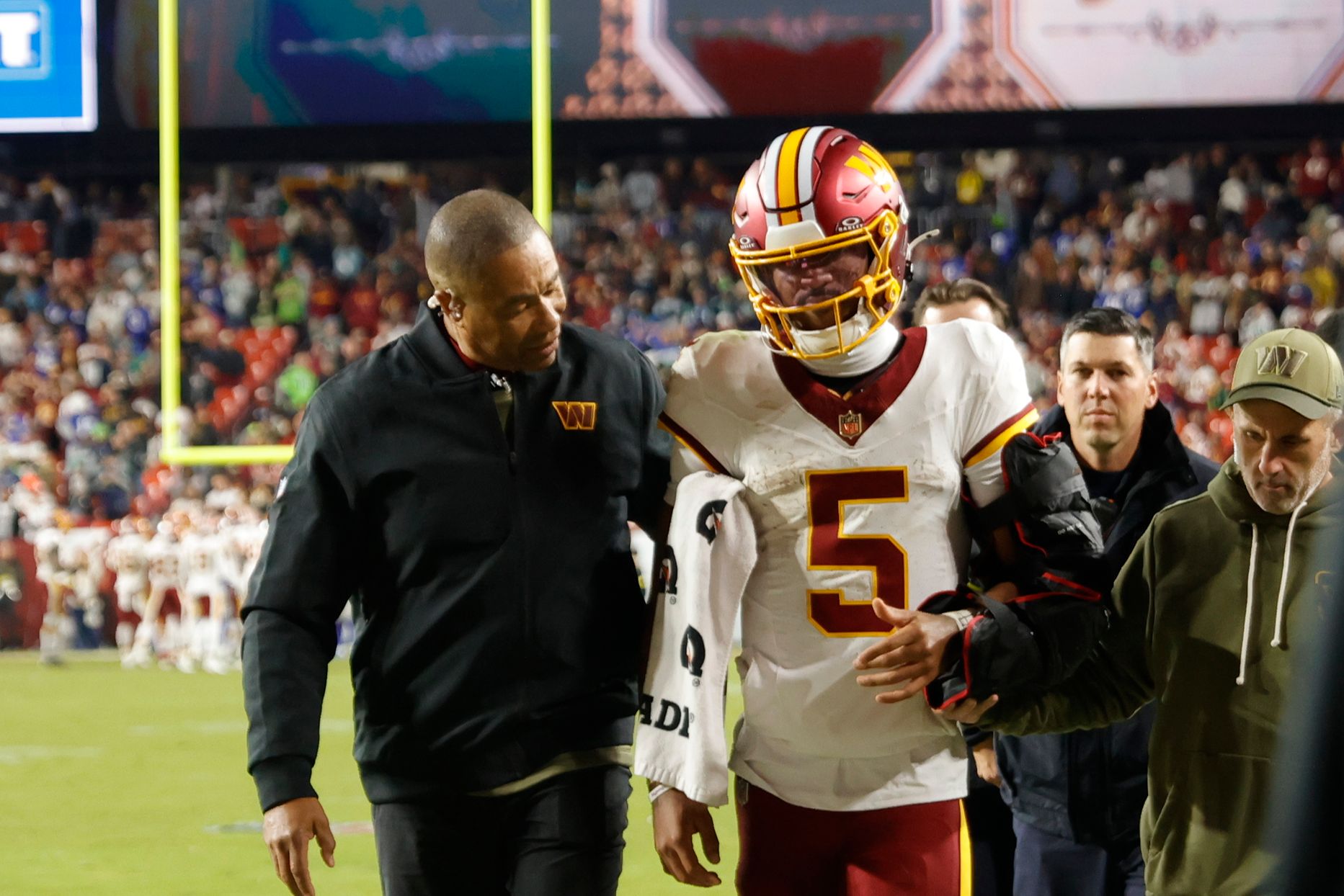 Washington Commanders quarterback Jayden Daniels (5) is helped off the field after an injury during the second half against the Seattle Seahawks at Northwest Stadium.