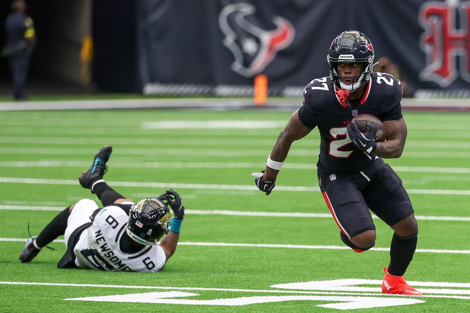 Houston Texans running back Woody Marks (27) rushes against Jacksonville Jaguars cornerback Greg Newsome II (6) in the second half at NRG Stadium.