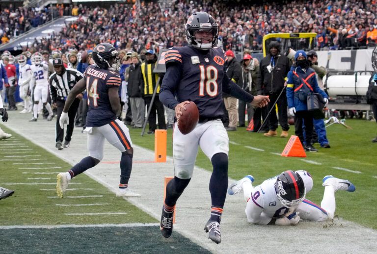 Chicago Bears quarterback Caleb Williams (18) scores the game-winning touchdown against New York Giants linebacker Brian Burns (0) during the fourth quarter at Soldier Field.