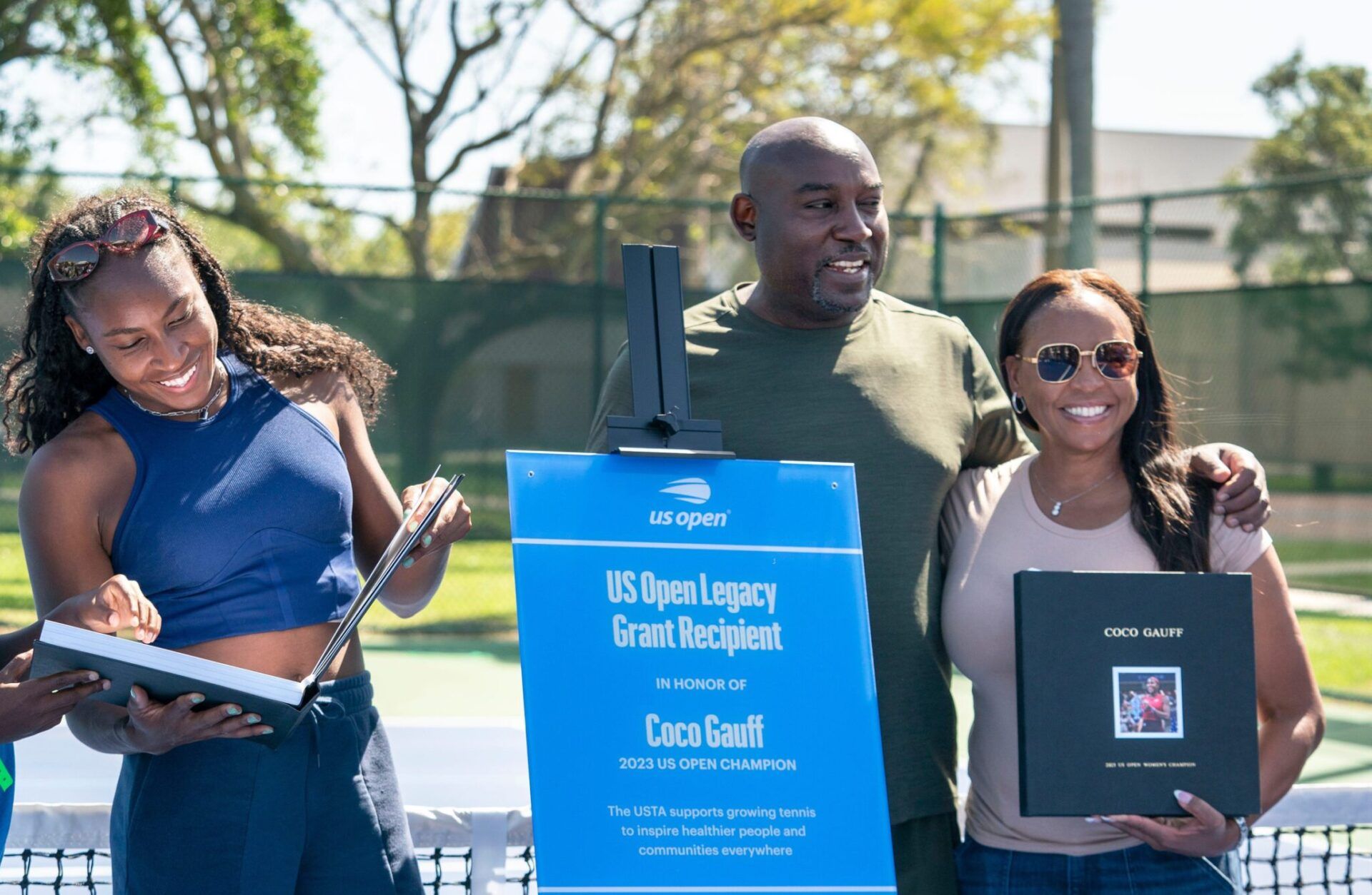 Coco Gauff and her brother Cameron Gauff, 10, looks a a gift book next to their parents Corey and Candi Gauff after a ceremony celebrating the two refurbished public tennis courts at Pompey Park as part of the US Open Legacy Initiative, which was created in honor of Gauff's 2023 U.S. Open women's singles on March 19, 2024 in Delray Beach, Florida.