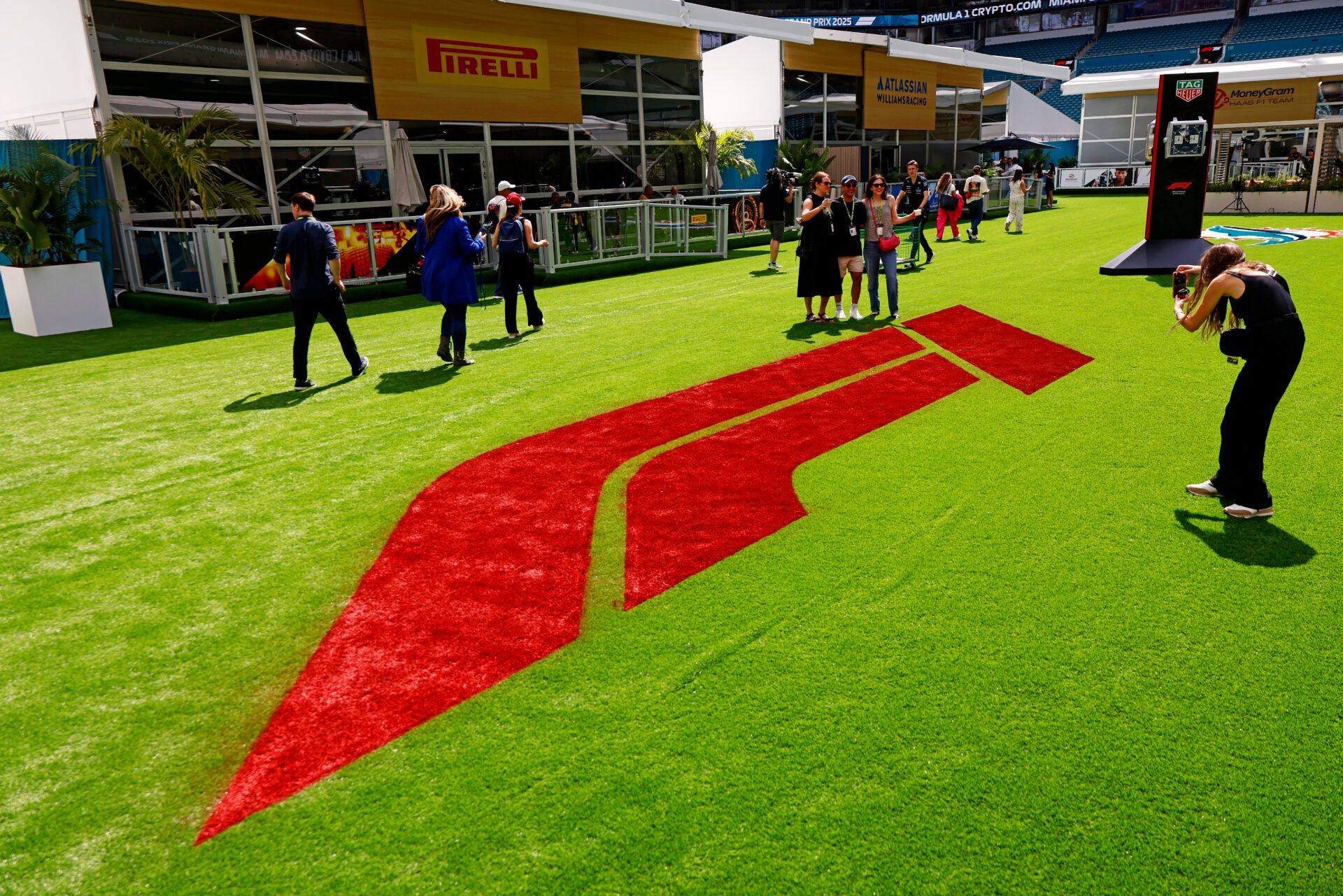 Fans pose for a picture in front of the F1 logo in the team village ahead of the F1 Miami Grand Prix at Miami International Autodrome.
