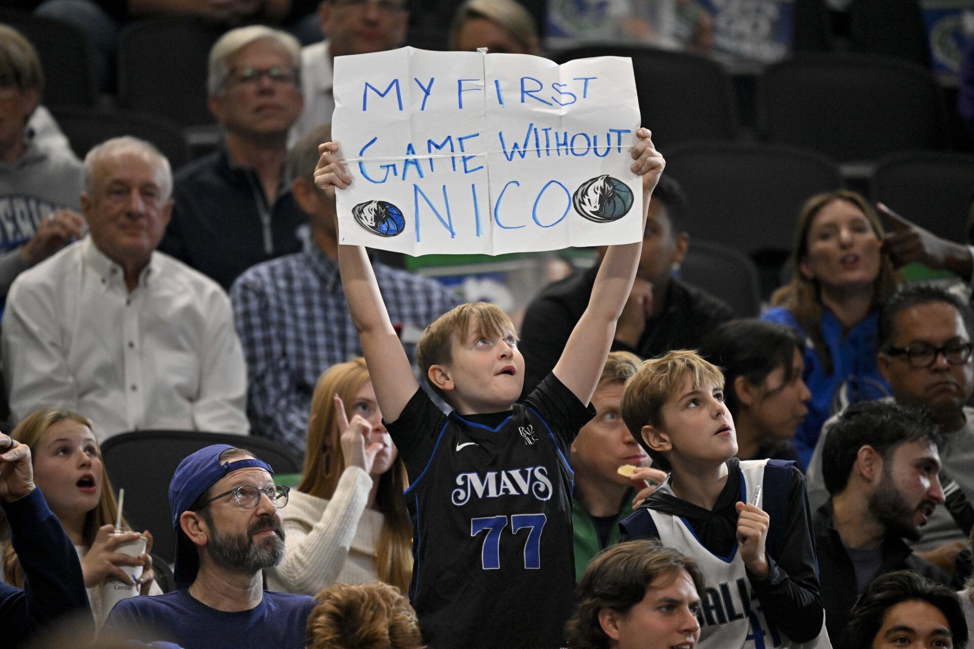 A young Dallas Mavericks fan in a Mavs Luka Doncic t-shirt holds up a sign referring to former general manager Nico Harrison during the game between the Dallas Mavericks and the Phoenix Suns at the American Airlines Center.