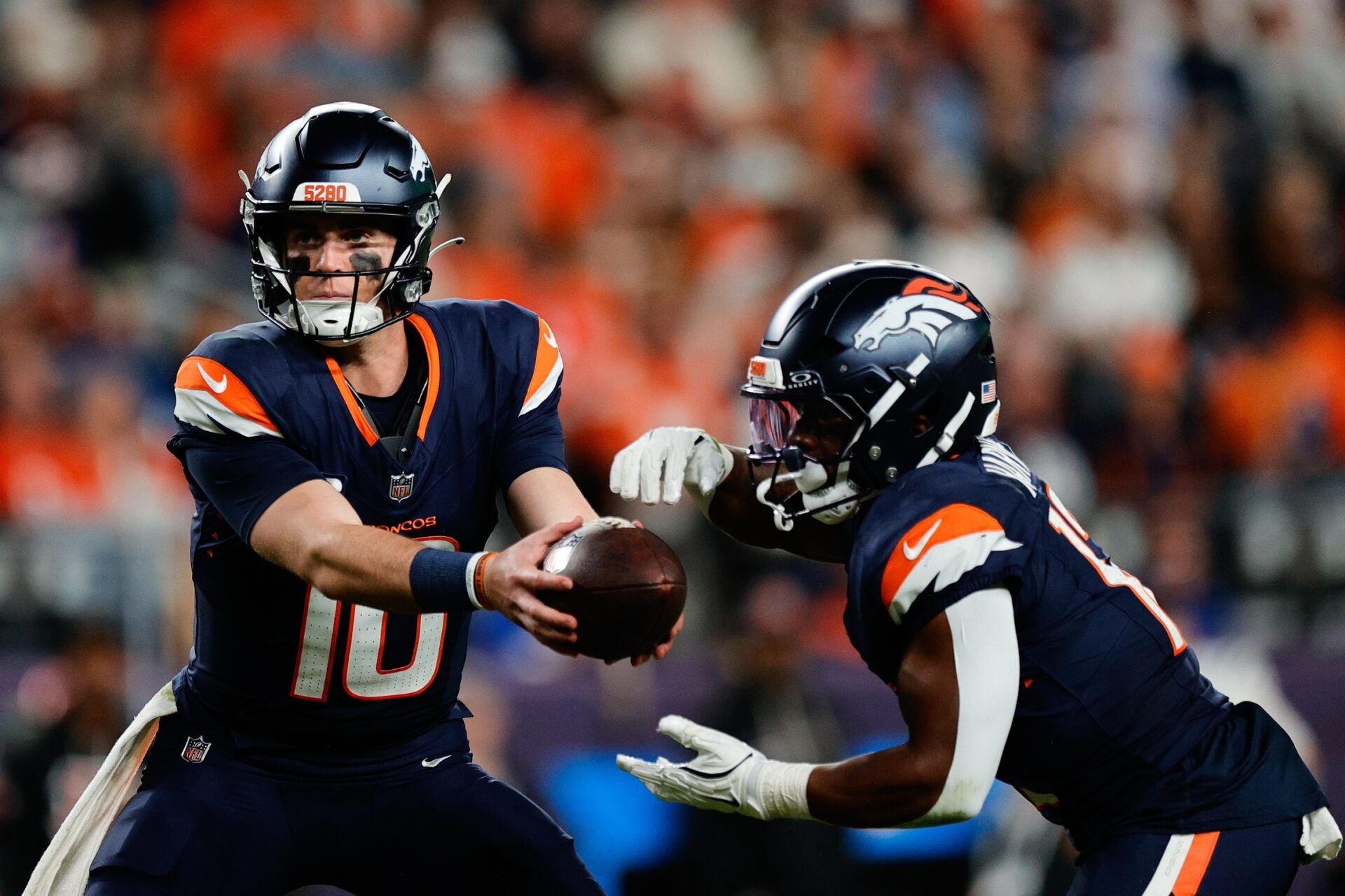 Denver Broncos quarterback Bo Nix (10) hands the ball off to Denver Broncos running back RJ Harvey (12) during the fourth quarter against the Cincinnati Bengals at Empower Field at Mile High.